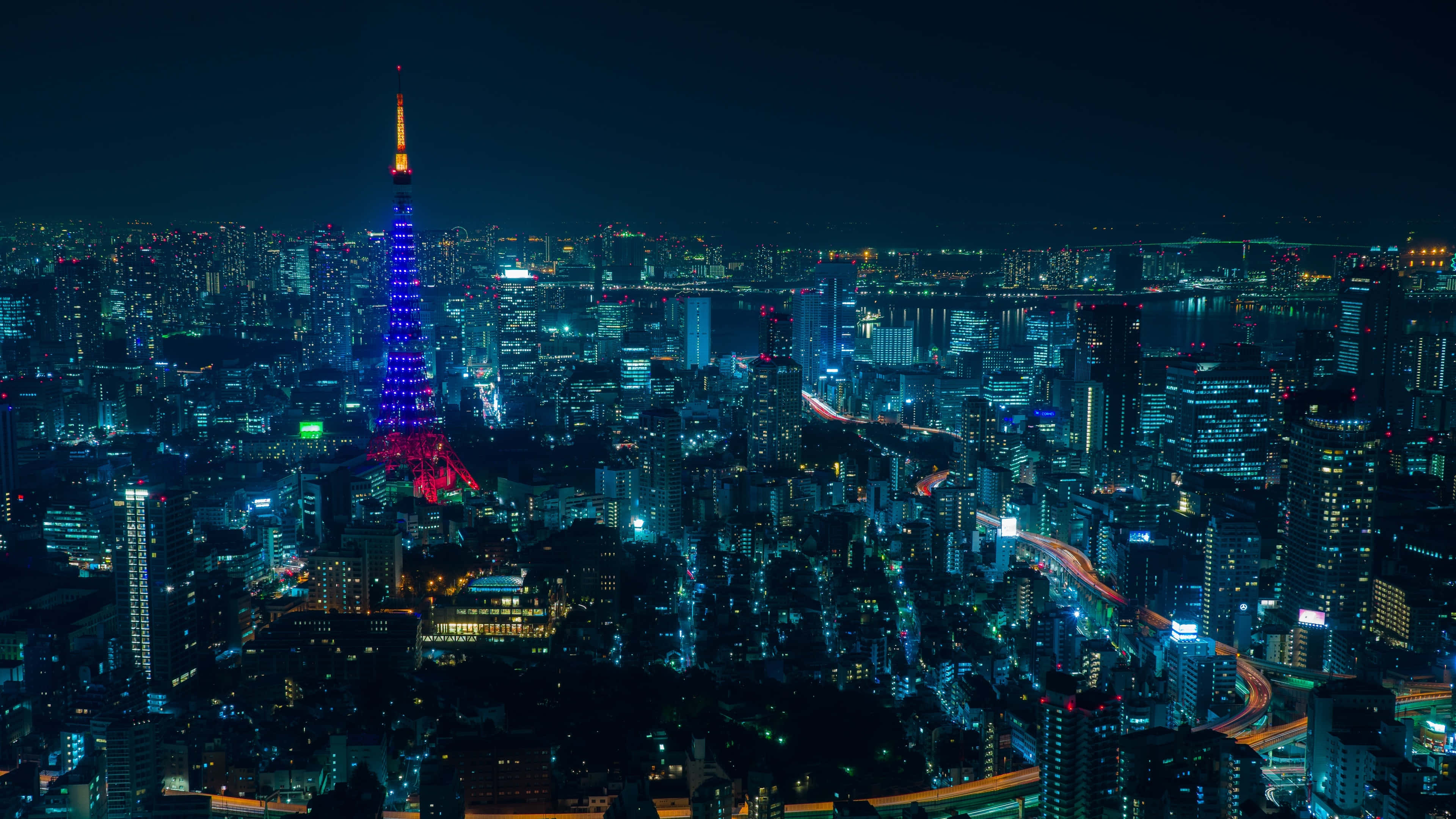 風景 桌布 壁紙 — 夜晚的東京天際線，東京塔在萬家燈火和明亮的高速公路中閃耀著藍色和紅色的光芒。
