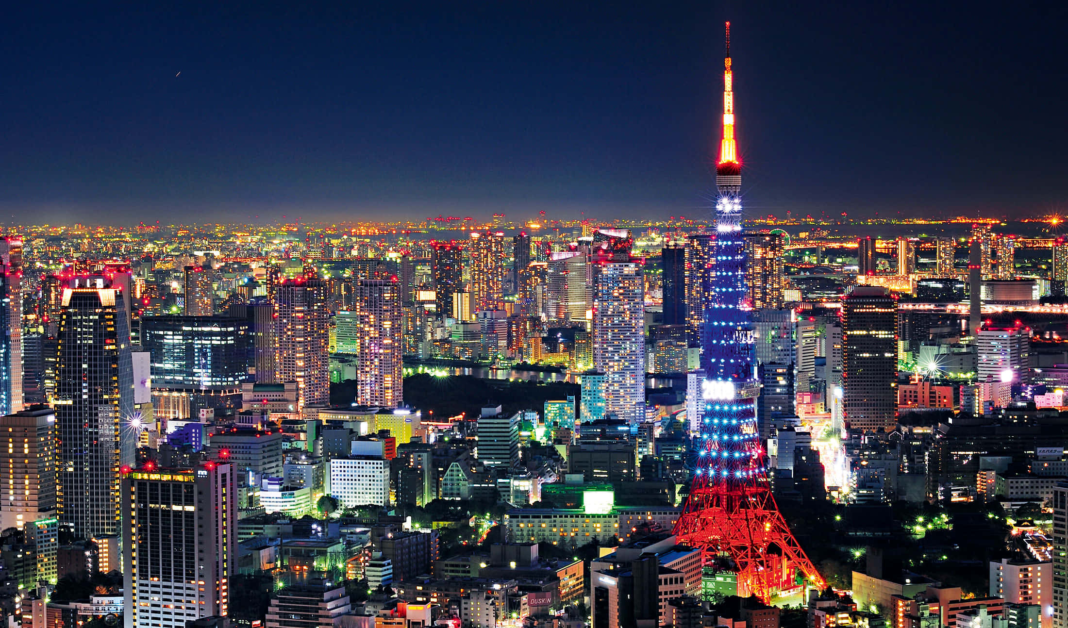 東京 桌布 壁紙 — 夜晚的東京天際線，東京塔在黑暗的天空中閃爍著紅色和藍色。