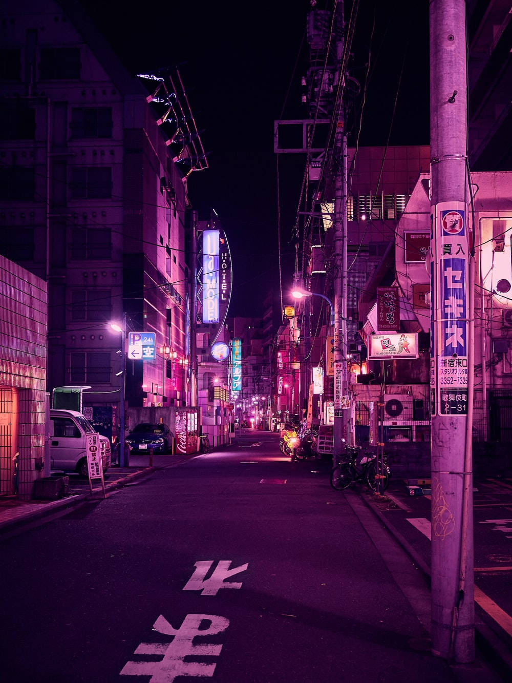粉紅色 桌布 壁紙 — 夜晚的東京小巷，霓虹燈光氾濫，紫色和粉紅色的燈光在潮濕的路面和雜亂的建築物上反射。