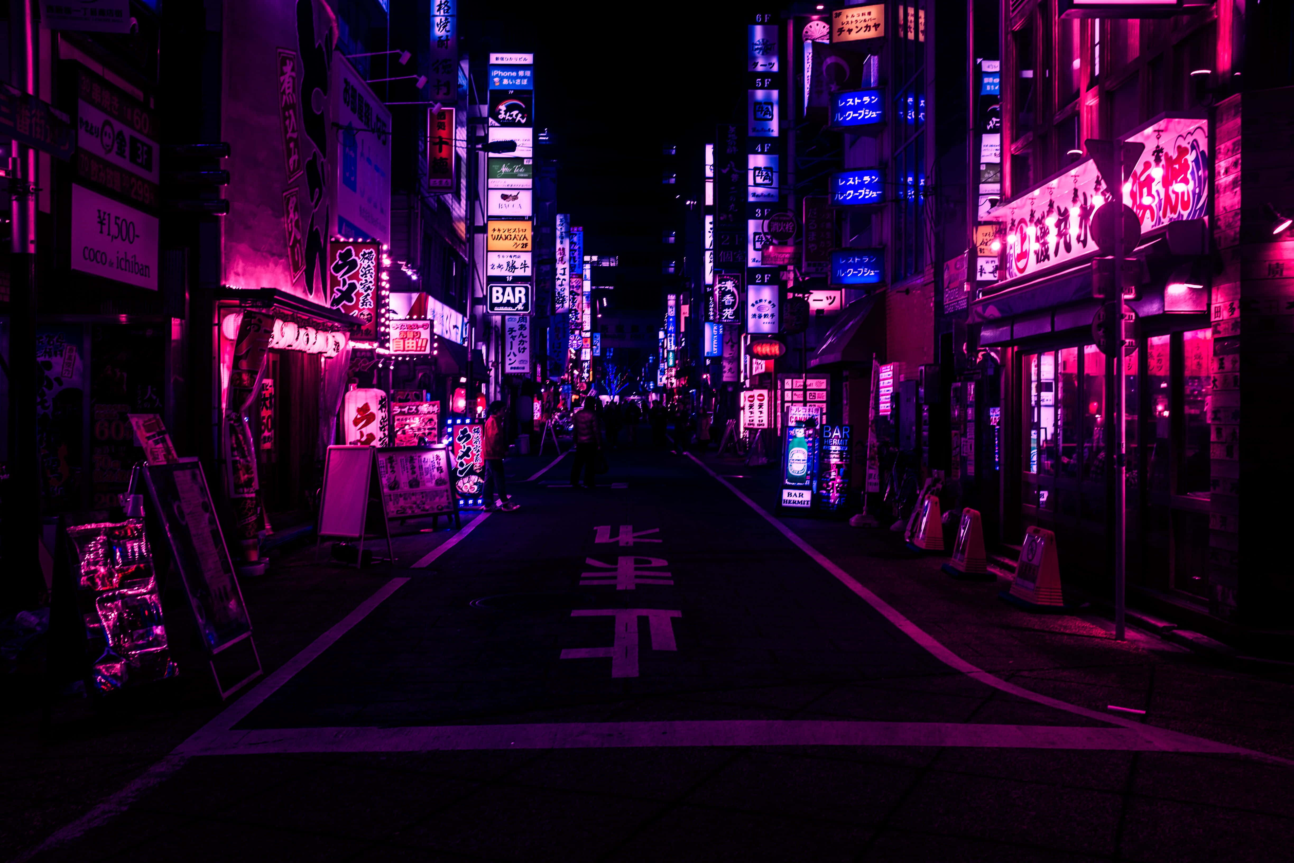 Japanese Aesthetic Black 桌布 壁紙 — 夜晚的東京小巷，霓虹燈光閃爍，粉紅色和藍色的招牌在潮濕的路面上投射出鮮豔的光芒。