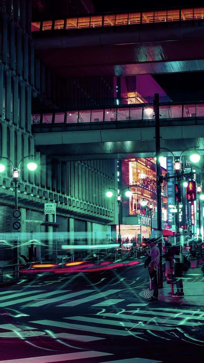 桌布 壁紙 — 夜晚的東京街道，霓虹燈光閃爍，綠色光芒橫跨斑馬線，行人於高聳建築物下等候。