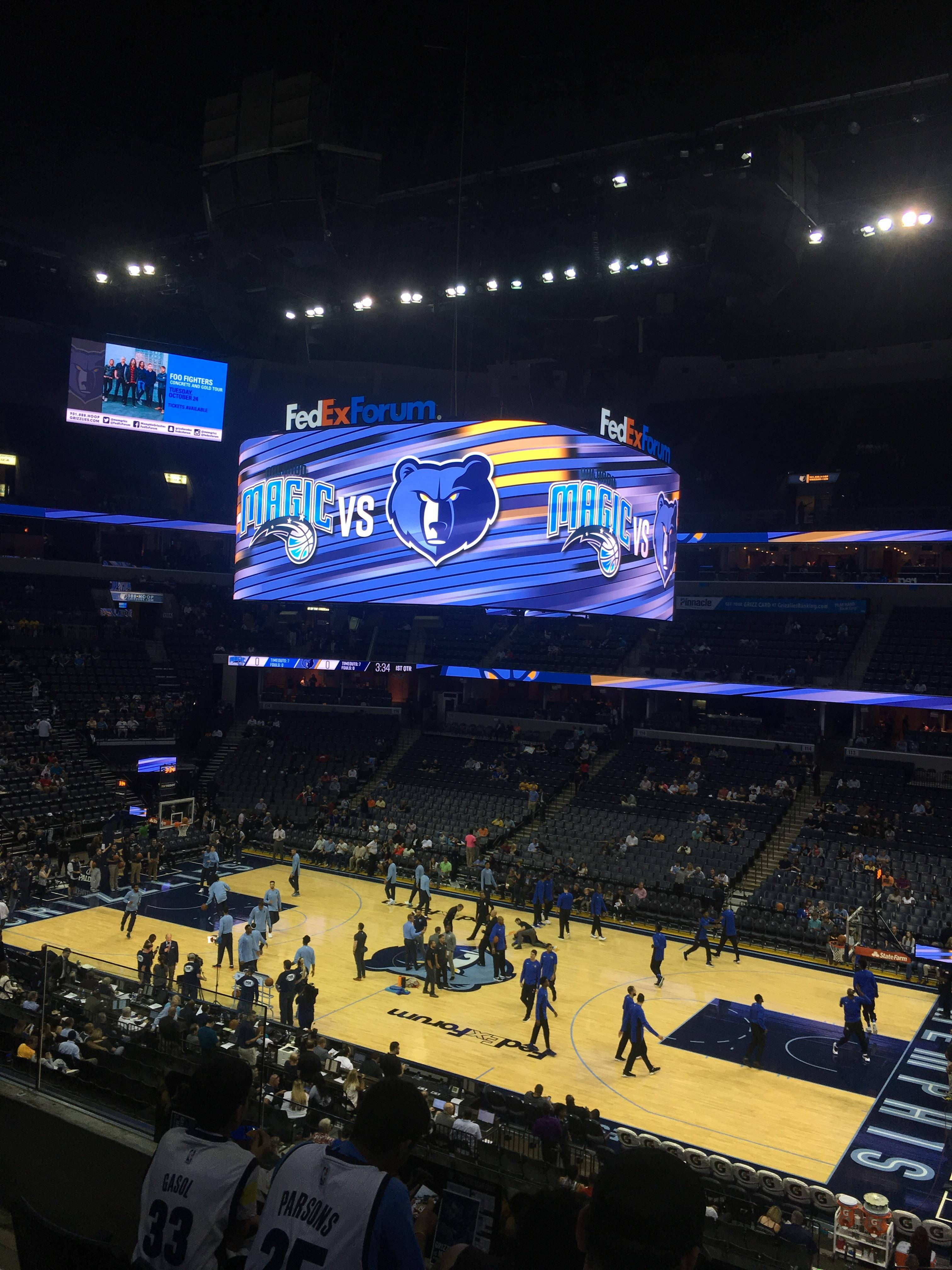 Grizzlies 桌布 壁紙 — 夜晚的籃球場，球員在明亮的燈光下熱身，記分牌顯示魔術對灰熊。