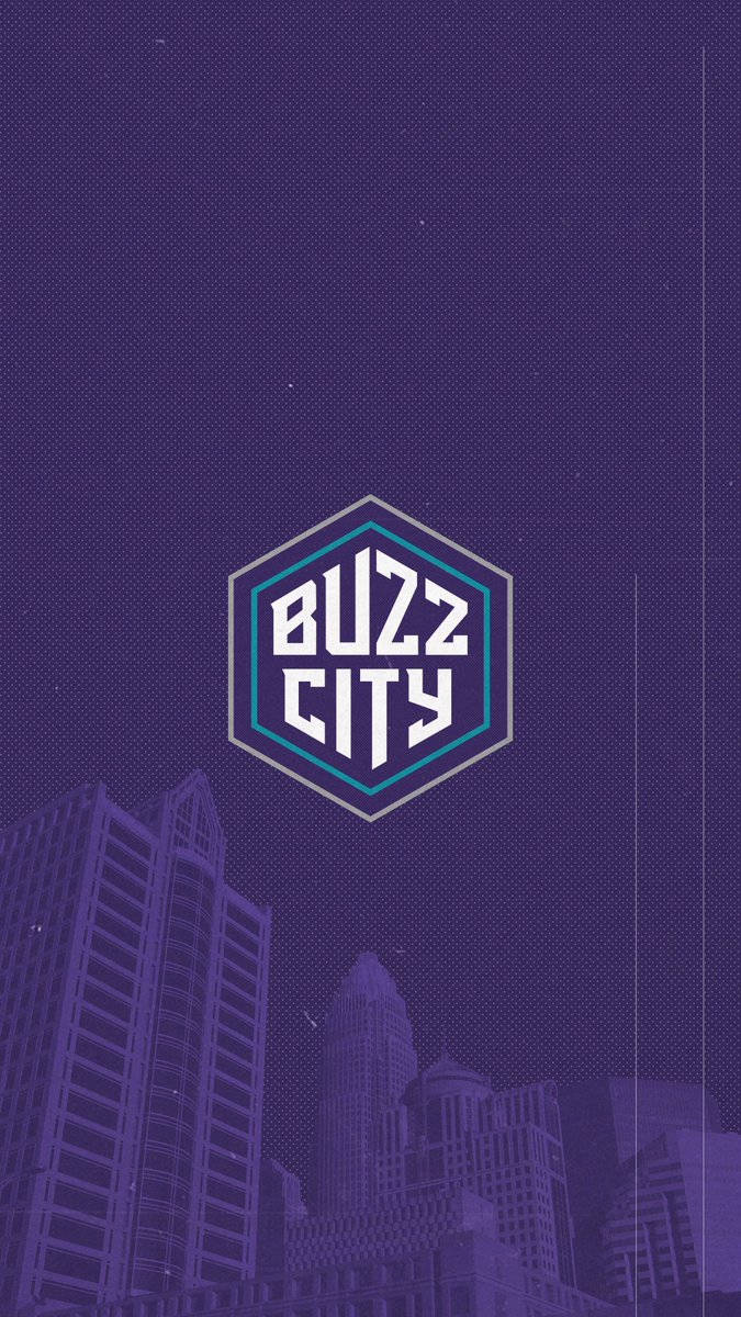 Hornets 桌布 壁紙 — 夜晚的紫色風格化城市景觀，摩天大樓上方中央有一個發光的六邊形「Buzz City」標誌。