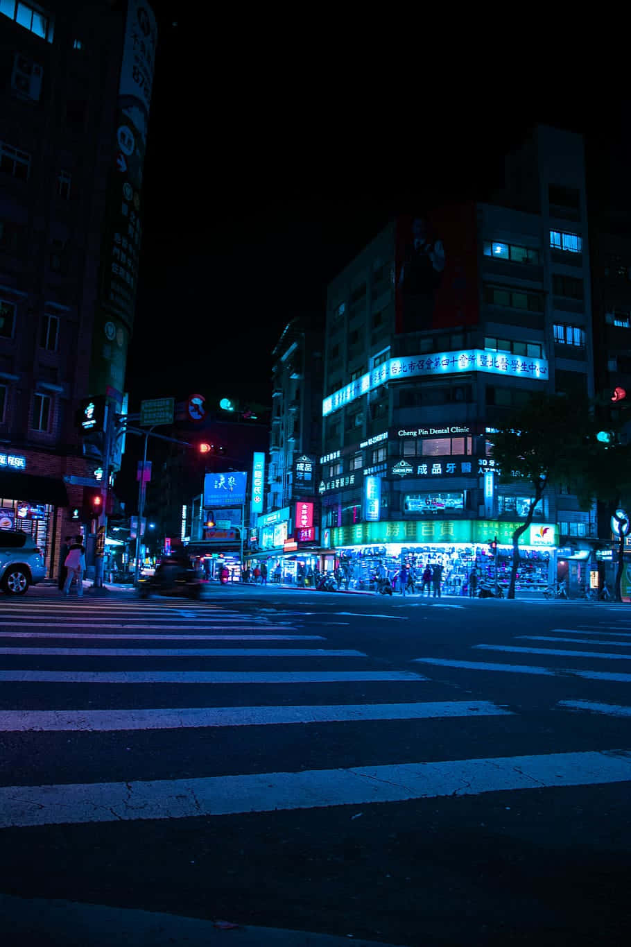 Night Street 桌布 壁紙 — 夜晚的霓虹燈城市街道，發光的招牌映照在濕漉漉的路面上，行人在黑暗的天空下過馬路。