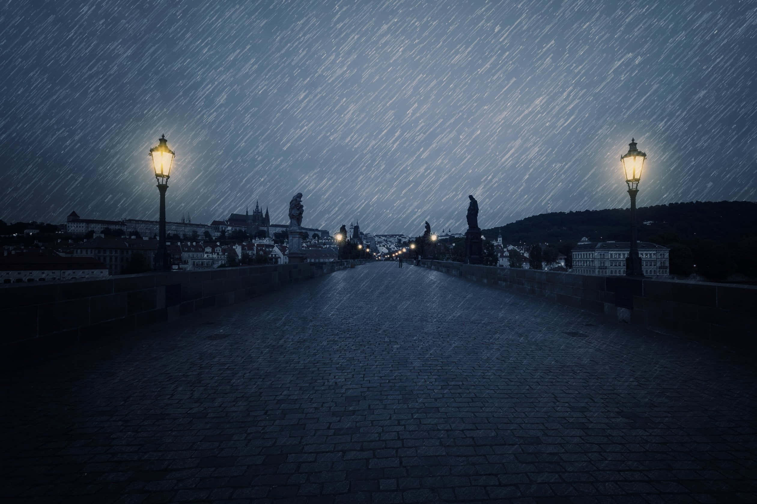 Rainy Day 桌布 壁紙 — 夜晚的鵝卵石橋，黑暗的天空中閃爍著街燈和雨絲。