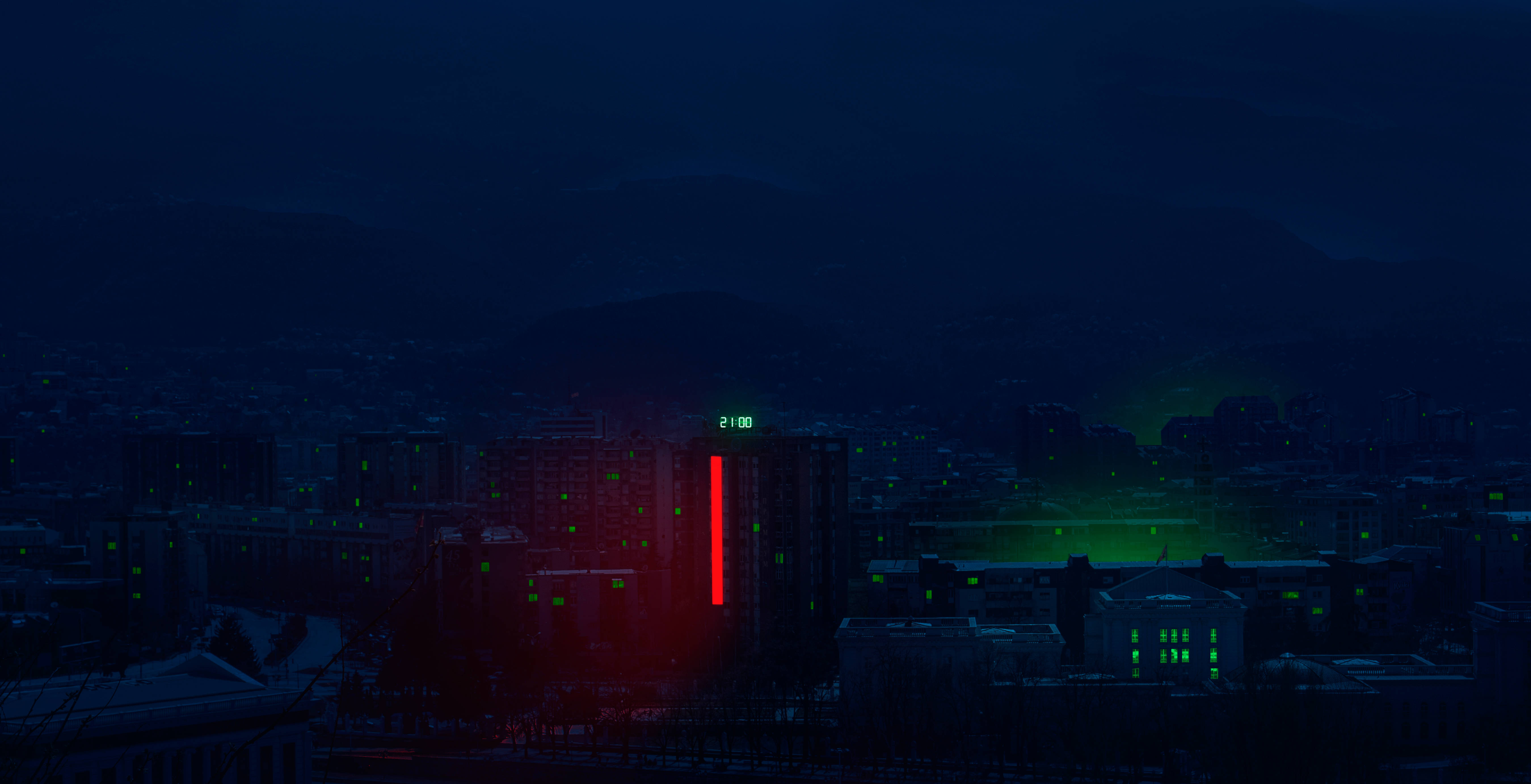 Macedonia 桌布 壁紙 — 夜晚的黑暗城市景觀，一座高樓發出紅色和綠色的光芒，背景是遠山。