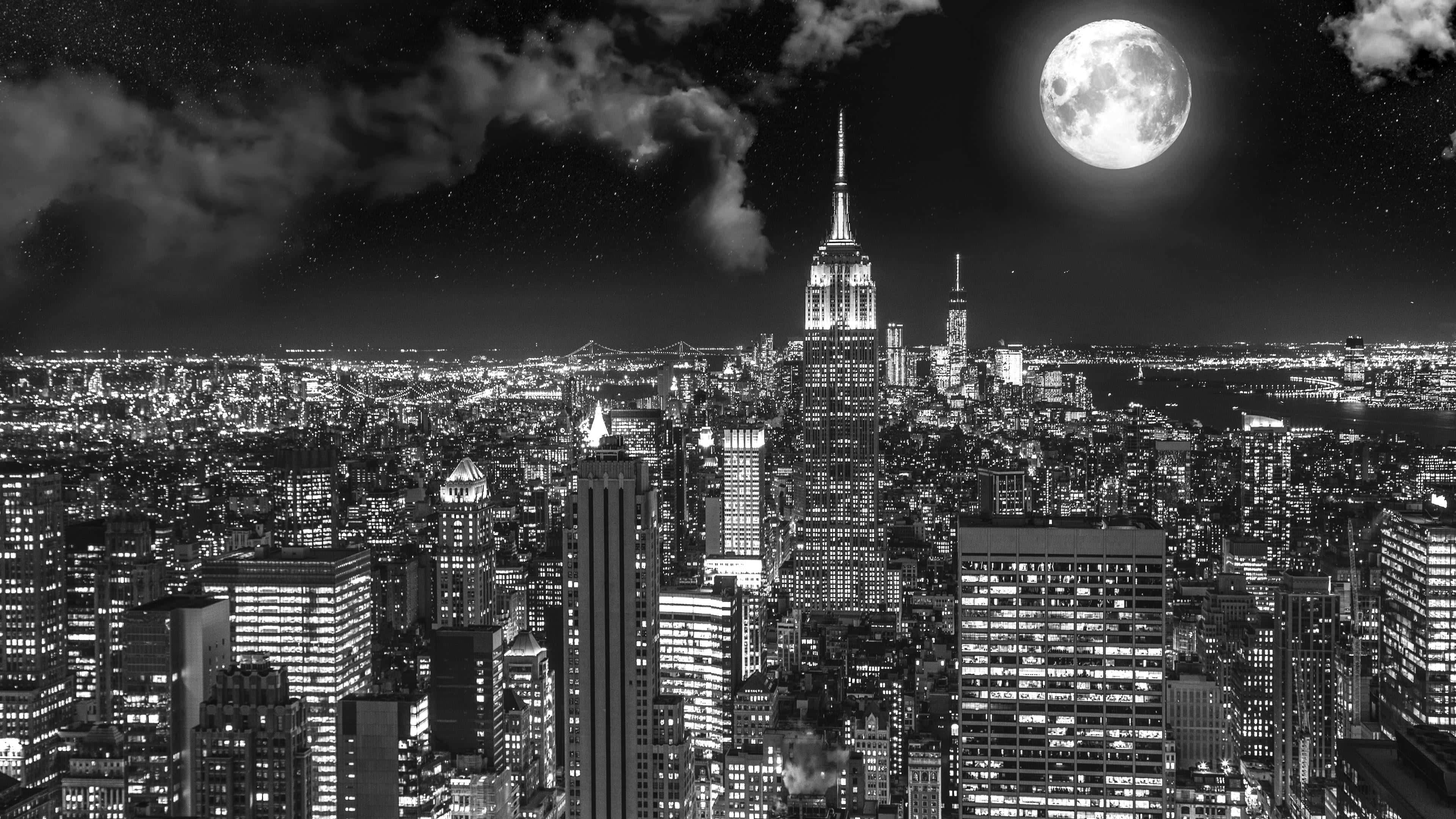 Black And White Cityscape 桌布 壁紙 — 夜晚的黑白城市景觀，滿月在照亮的高樓大廈上方閃耀。