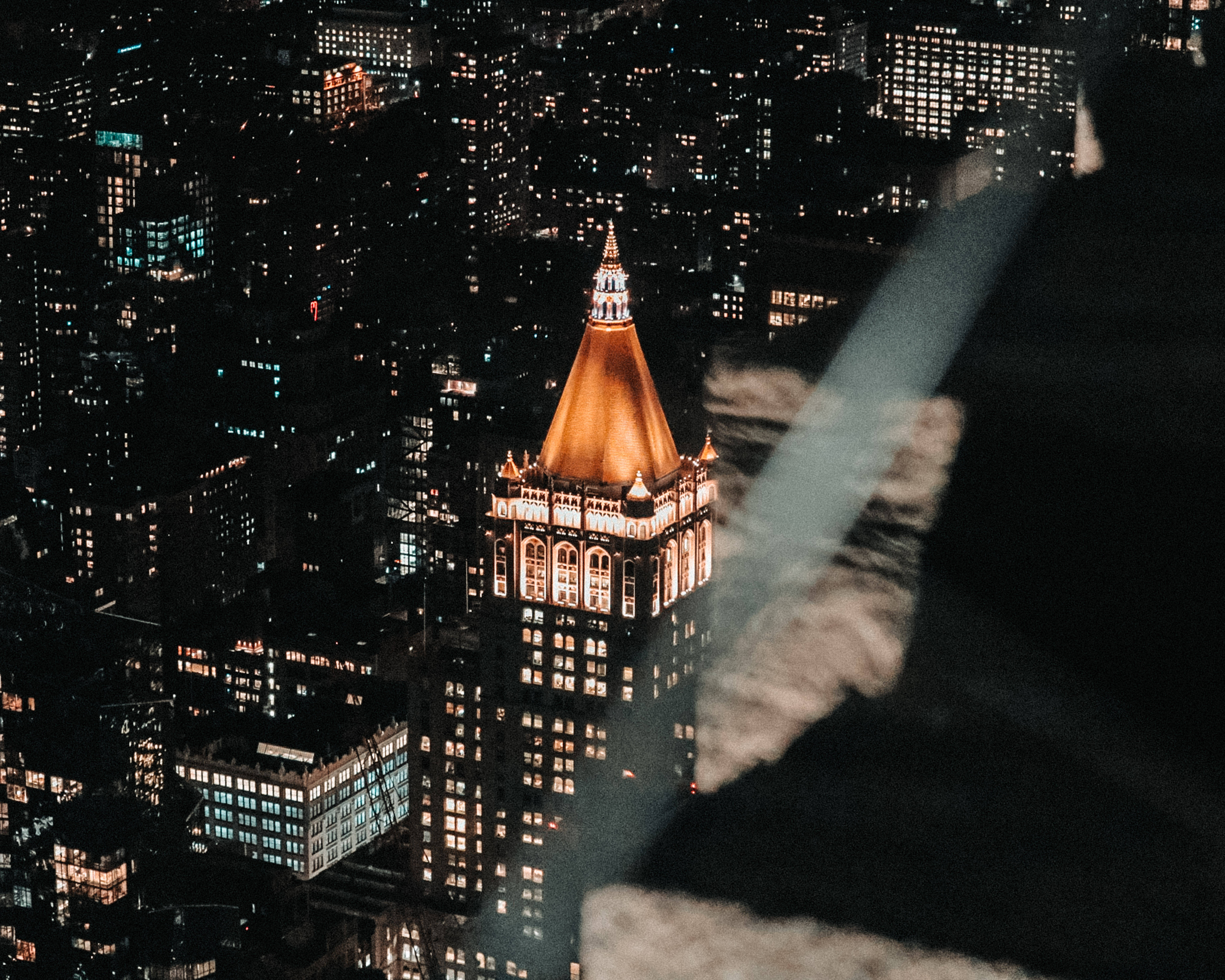 empire state 桌布 壁紙 — 夜晚空中俯瞰一座發光的摩天大樓，金色圓頂在黑暗的城市建築中脫穎而出。