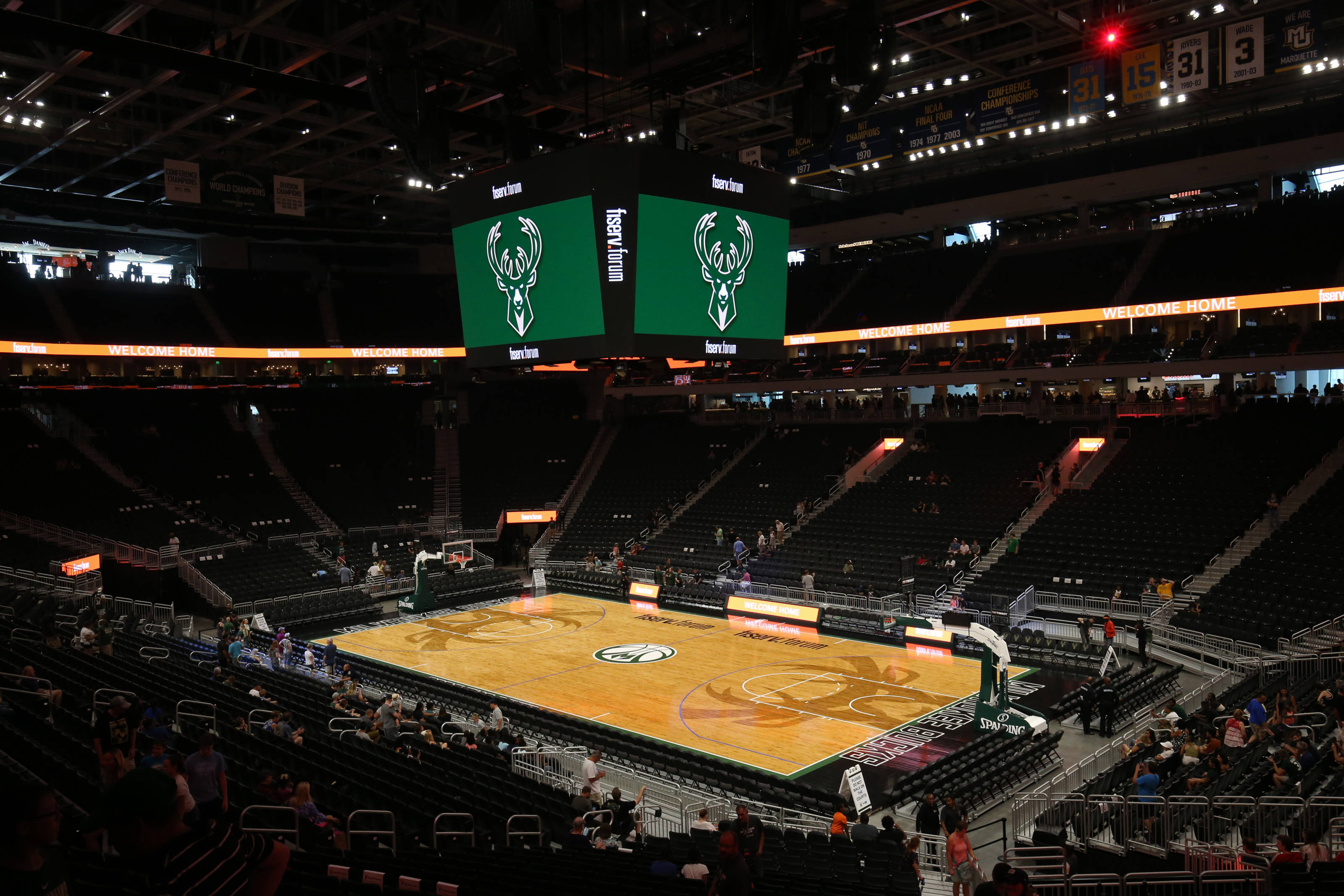 Bucks 桌布 壁紙 — 夜晚空無一人的籃球場，發光的球場和顯示鹿標誌的大型綠色螢幕。