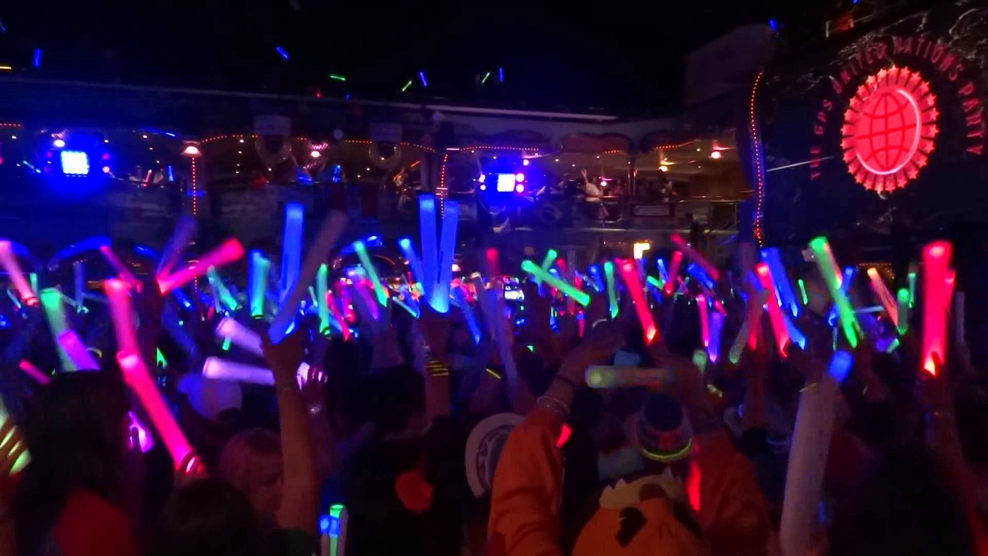 Party 桌布 壁紙 — 夜晚節日的人群在舞台燈光下揮舞色彩繽紛的發光棒。