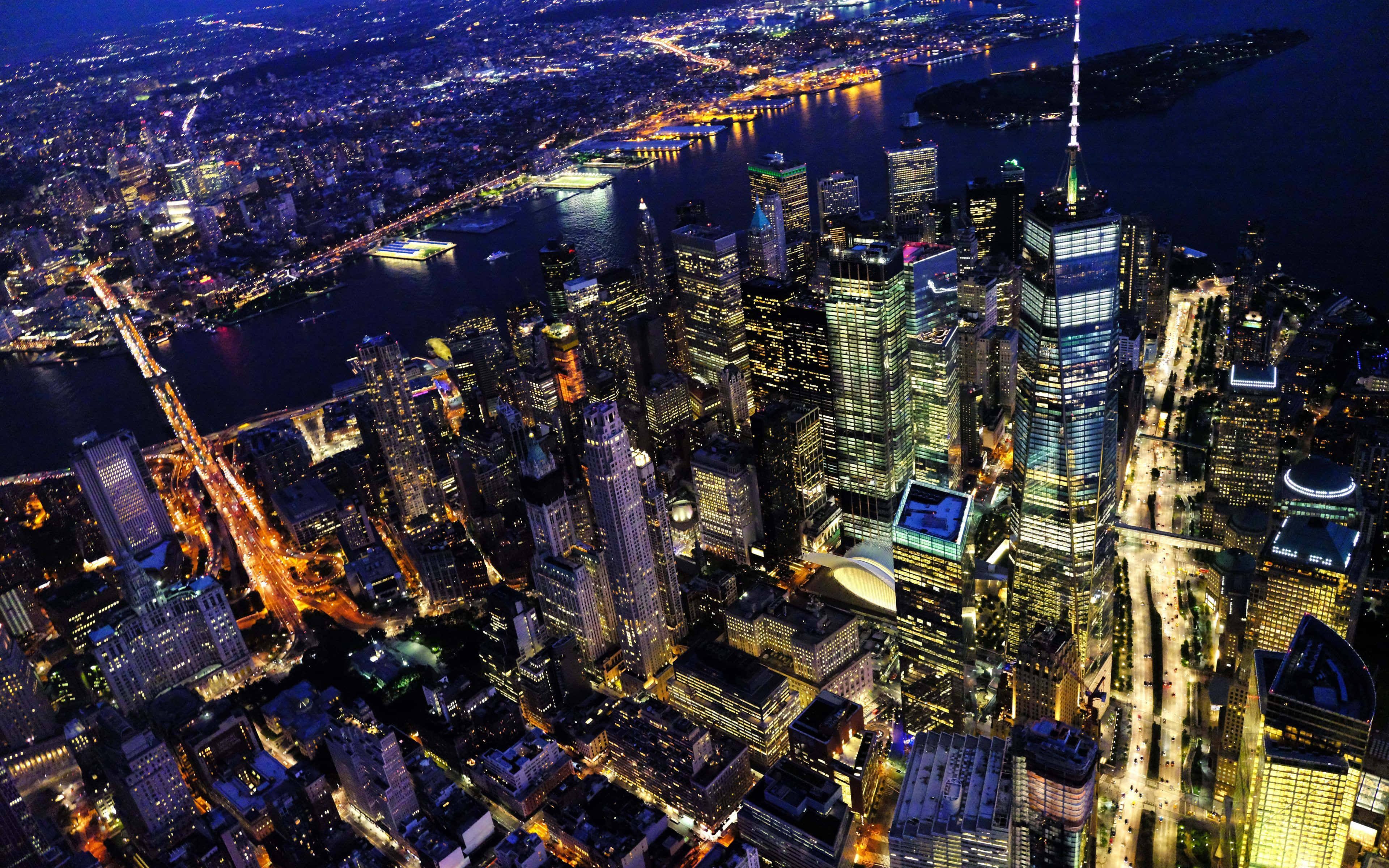 紐約市 桌布 壁紙 — 夜晚紐約市的鳥瞰圖，閃爍的摩天大樓和黑暗水面上燈火通明的橋樑。