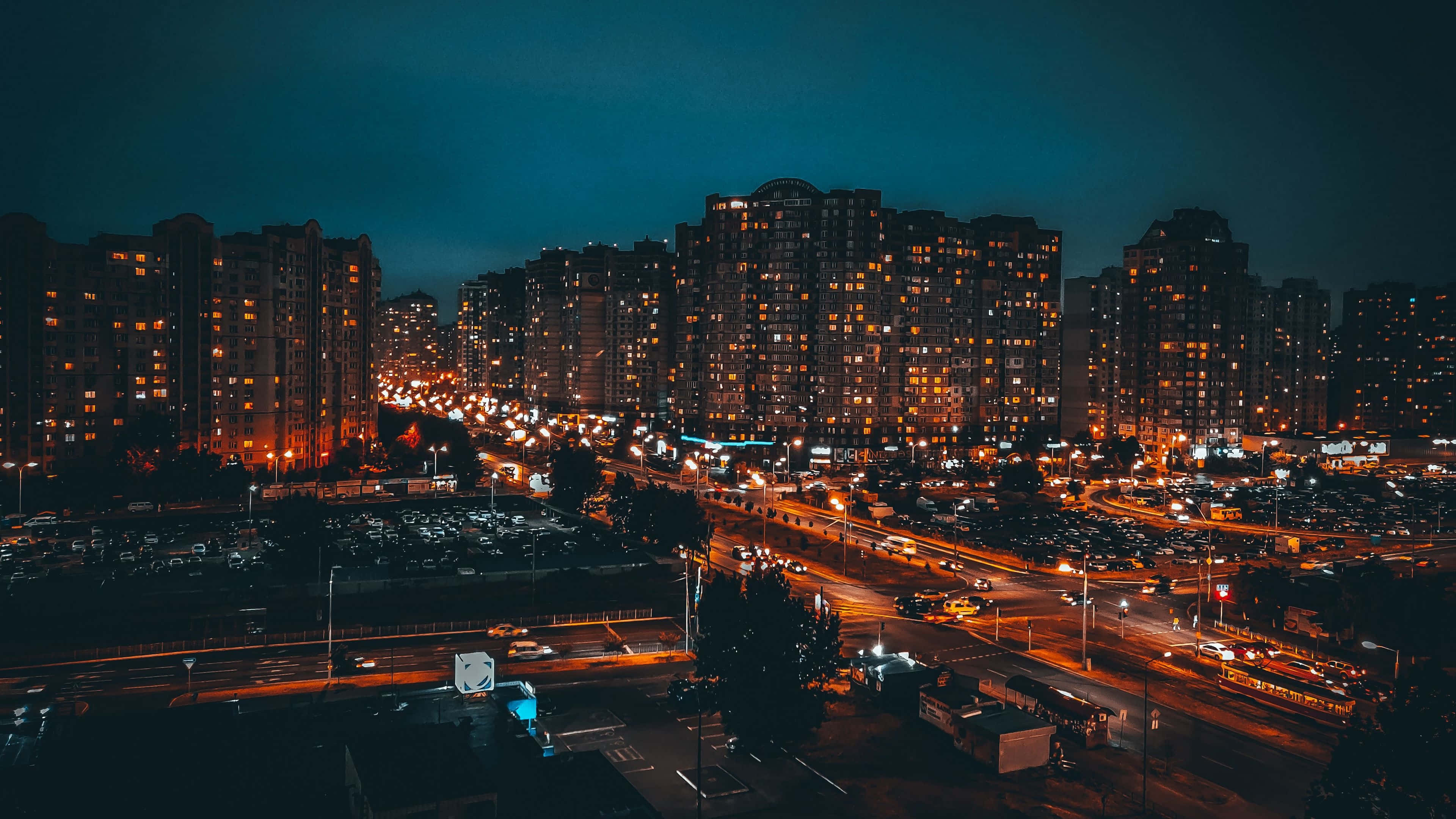 城市 桌布 壁紙 — 夜晚繁忙城市的鳥瞰圖，發光的窗戶和汽車燈光劃過街道。