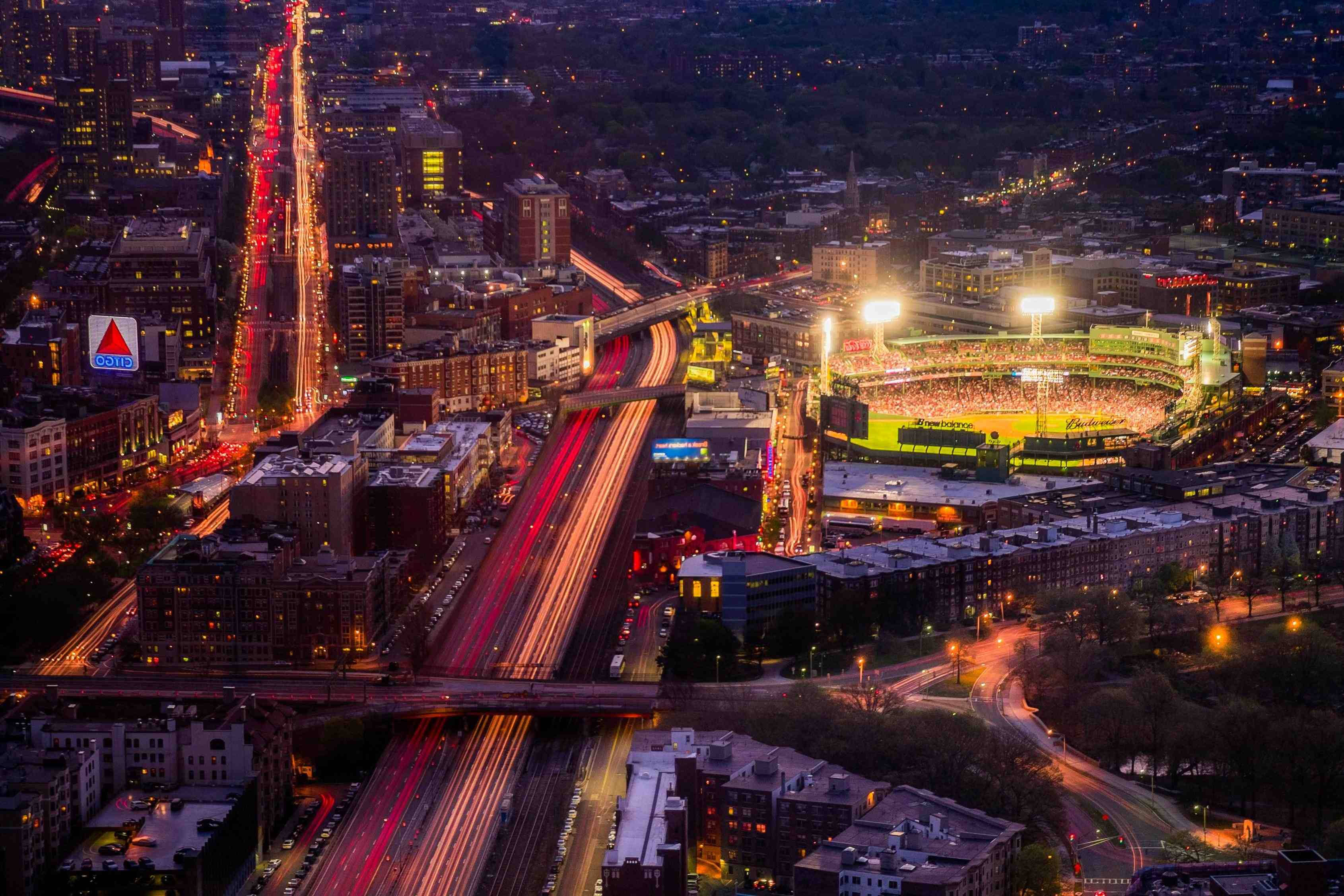 Boston 桌布 壁紙 — 夜晚繁忙城市的鳥瞰圖，發光的體育場和流動的交通燈光軌跡。
