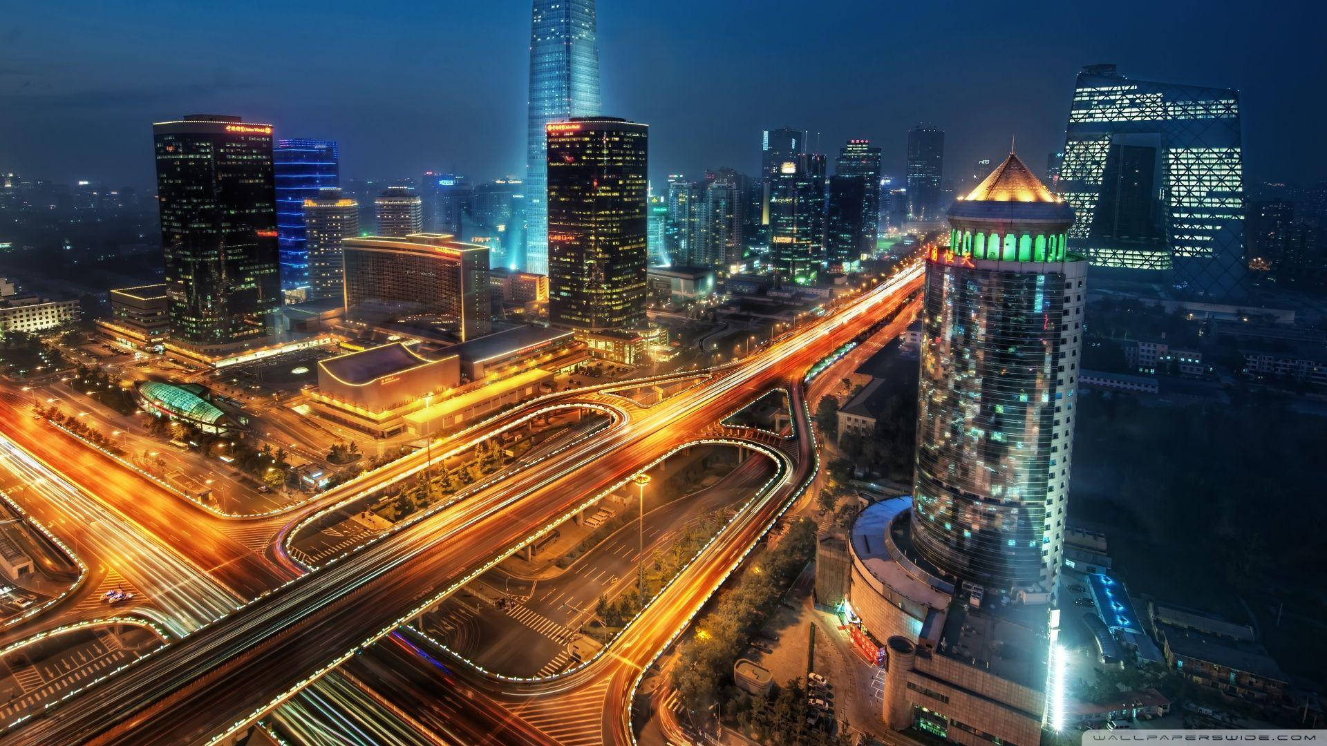Beijing 桌布 壁紙 — 夜晚繁忙城市的鳥瞰圖，閃爍的摩天大樓和蜿蜒高速公路上車流的光跡。