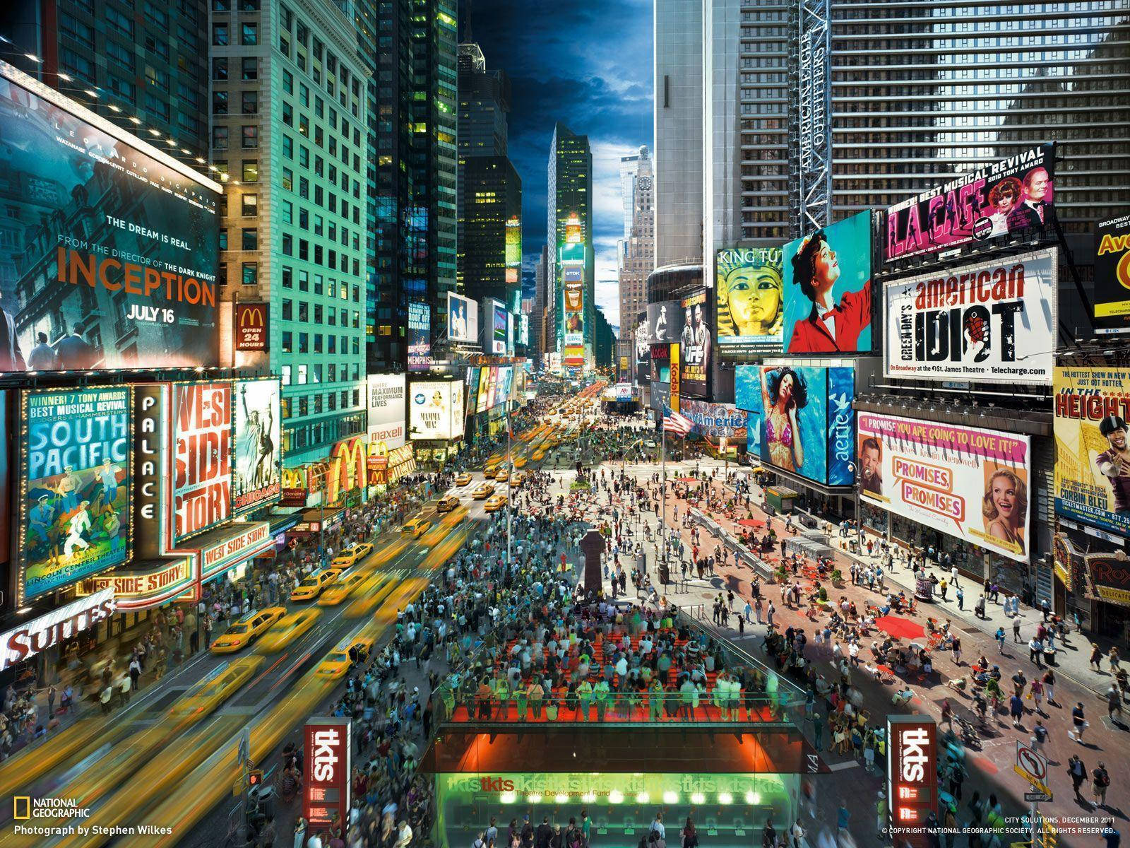Broadway 桌布 壁紙 — 夜晚繁忙的時代廣場，高聳的建築物在霓虹燈牌下閃耀，人群熙攘。