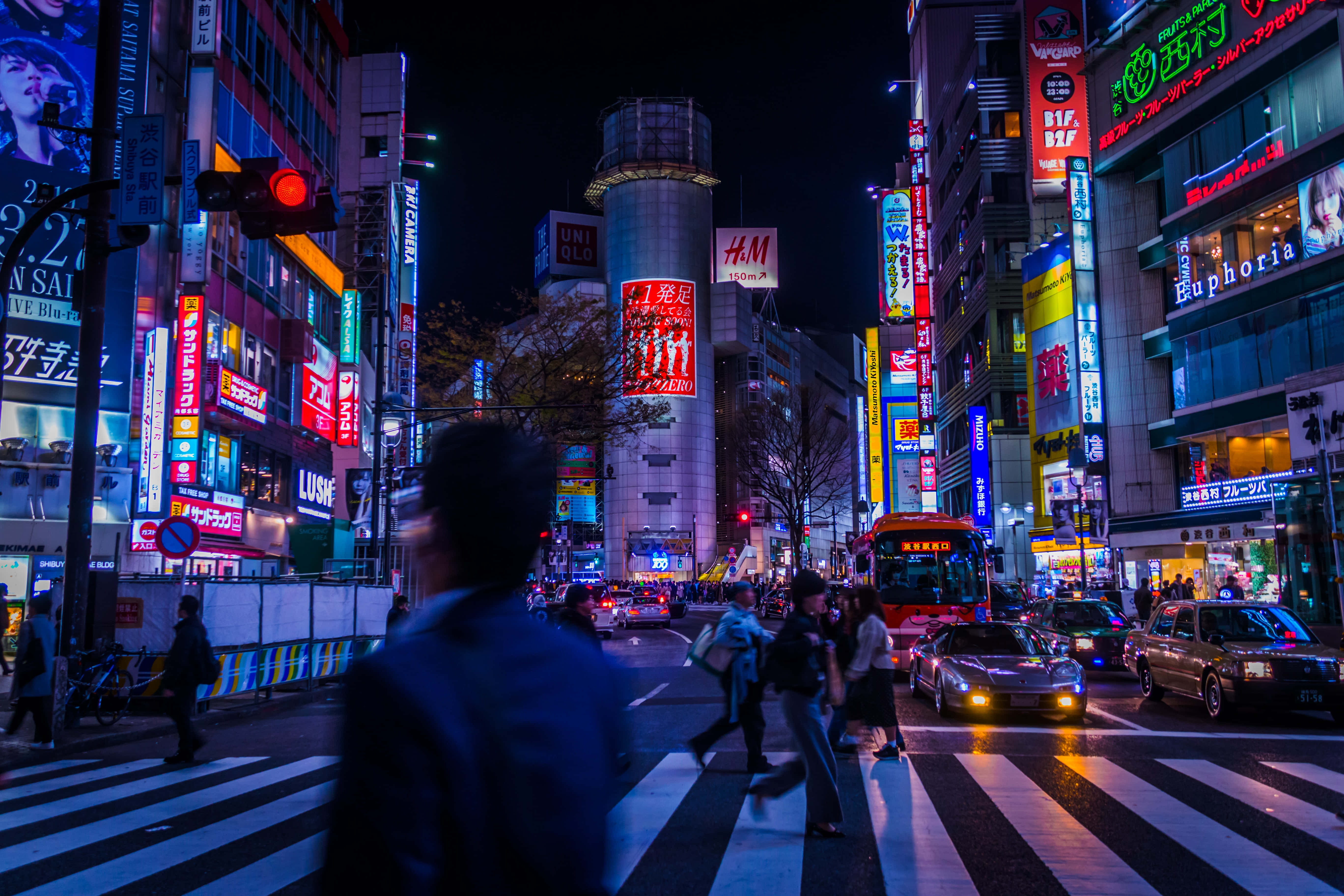 低傳真 桌布 壁紙 — 夜晚繁忙的東京街道，被鮮豔的霓虹燈和發光的廣告牌照亮，倒映在濕漉漉的人行道上。