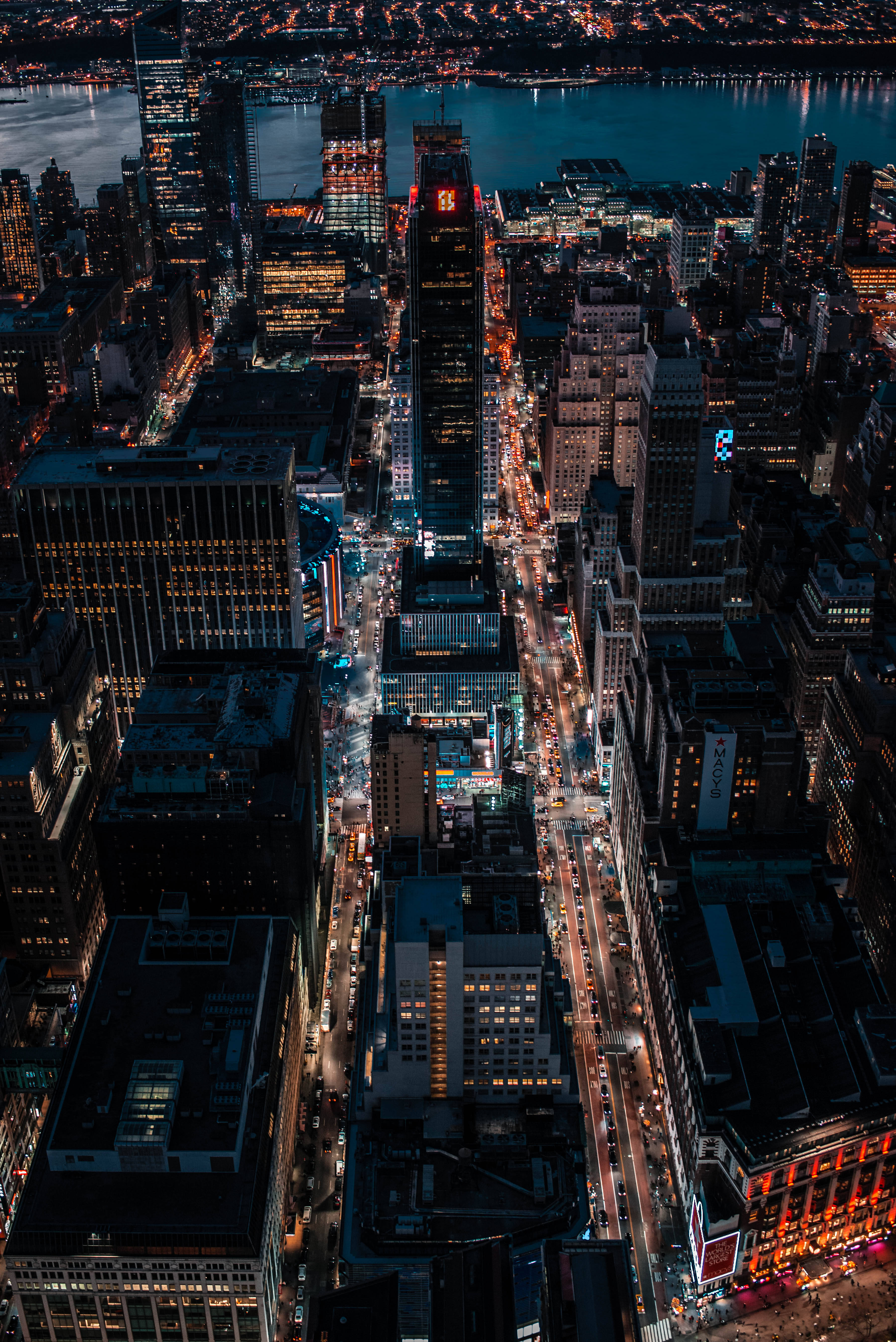 empire state 桌布 壁紙 — 夜晚繁華城市的鳥瞰圖，閃爍的摩天大樓和燈火通明的街道倒映在水面上。