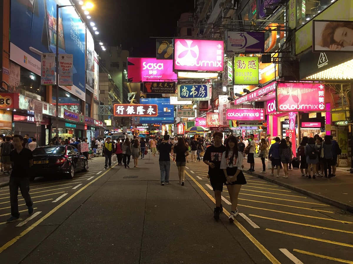 Street 桌布 壁紙 — 夜晚繁華的霓虹燈街道，密集的城市區域中，人群走過發光的商店招牌。