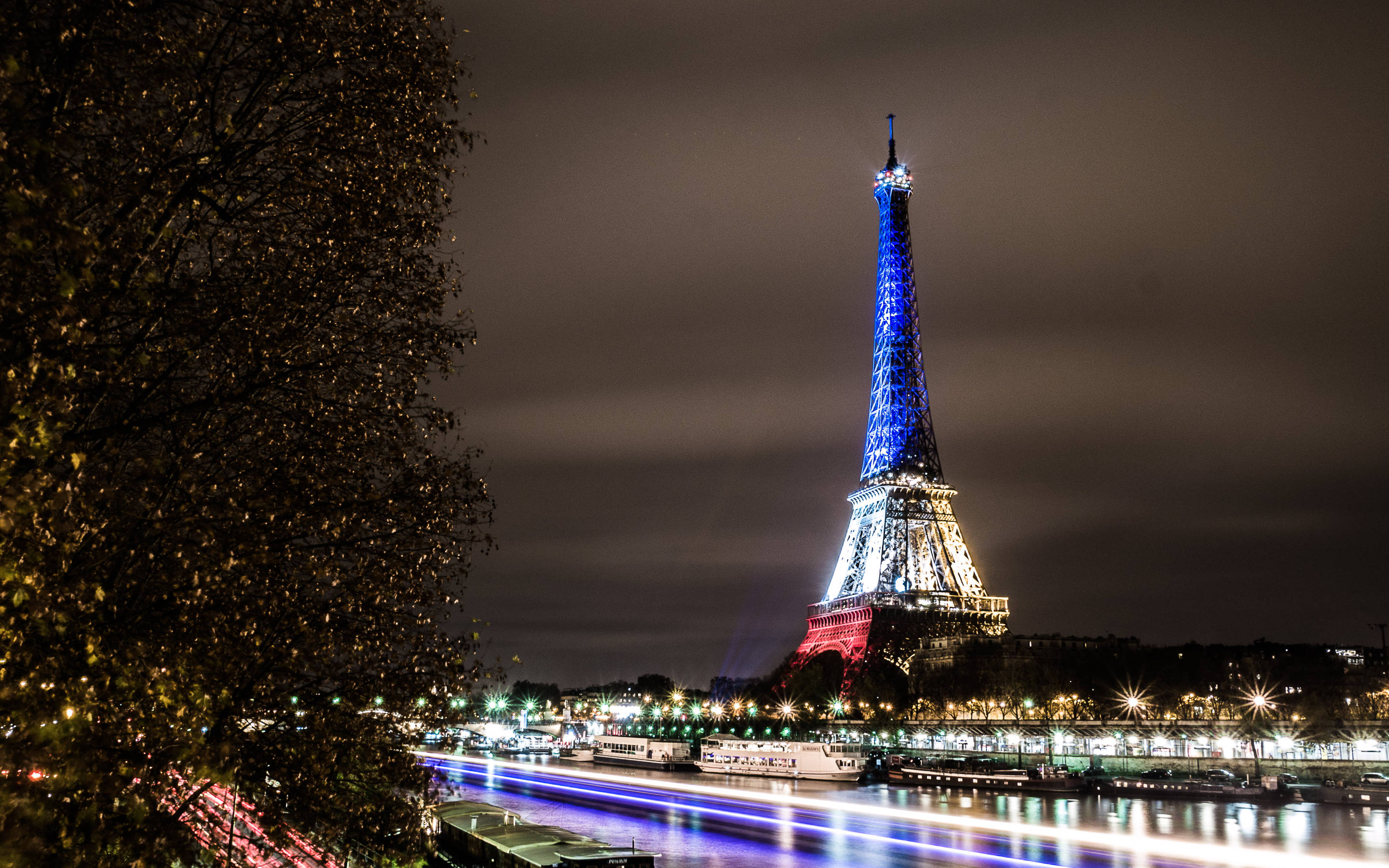 France Flag 桌布 壁紙 — 夜晚艾菲爾鐵塔以藍、白、紅燈光點亮，塞納河上船隻留下光跡。