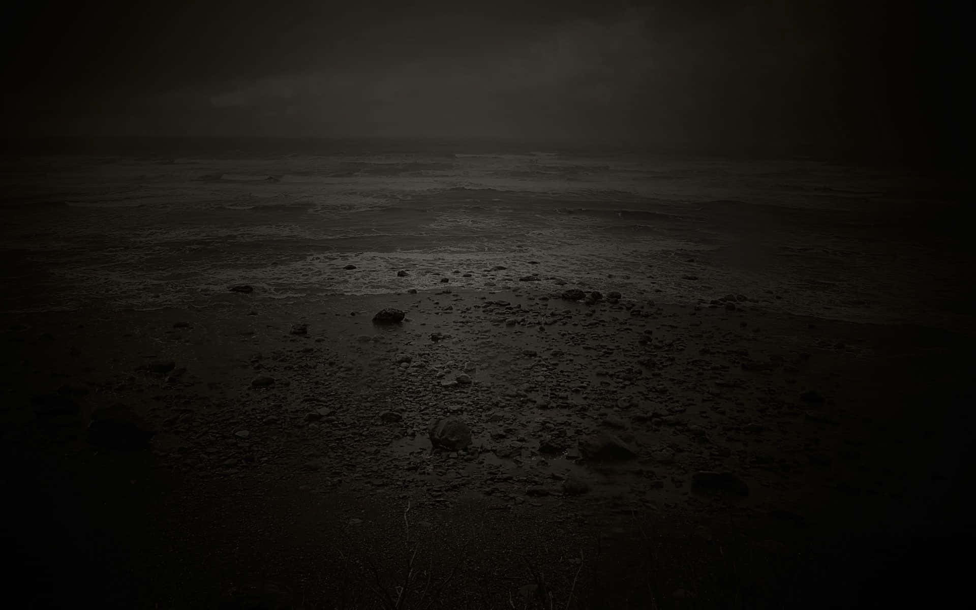 Dark Emotional 桌布 壁紙 — 夜晚荒涼的黑暗海灘，濕沙、岩石和暴風雨的天空在黑暗中幾乎看不見。