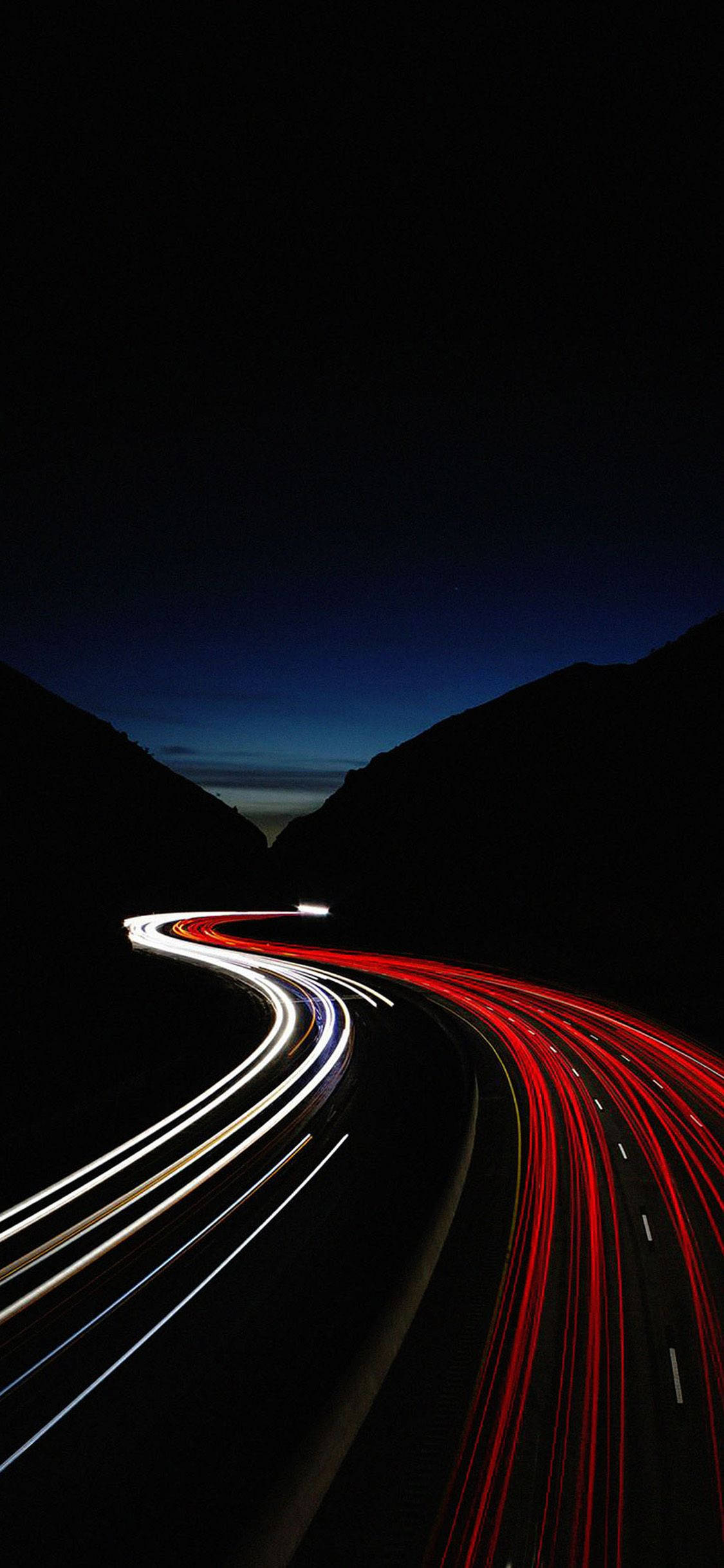 Road 桌布 壁紙 — 夜晚蜿蜒的山路，被紅色和白色車燈的條紋照亮，映襯著黑暗的輪廓山峰。