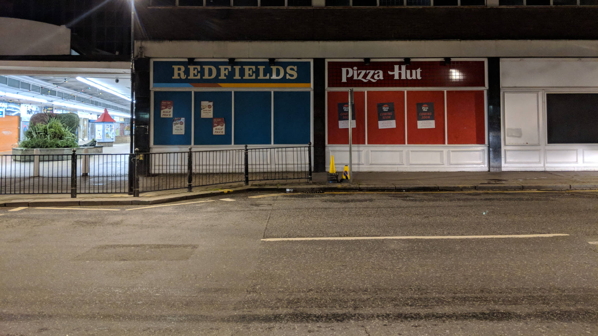 Hut 桌布 壁紙 — 夜晚街景，關閉的Redfields和Pizza Hut店面在人工燈光下，路面濕滑。