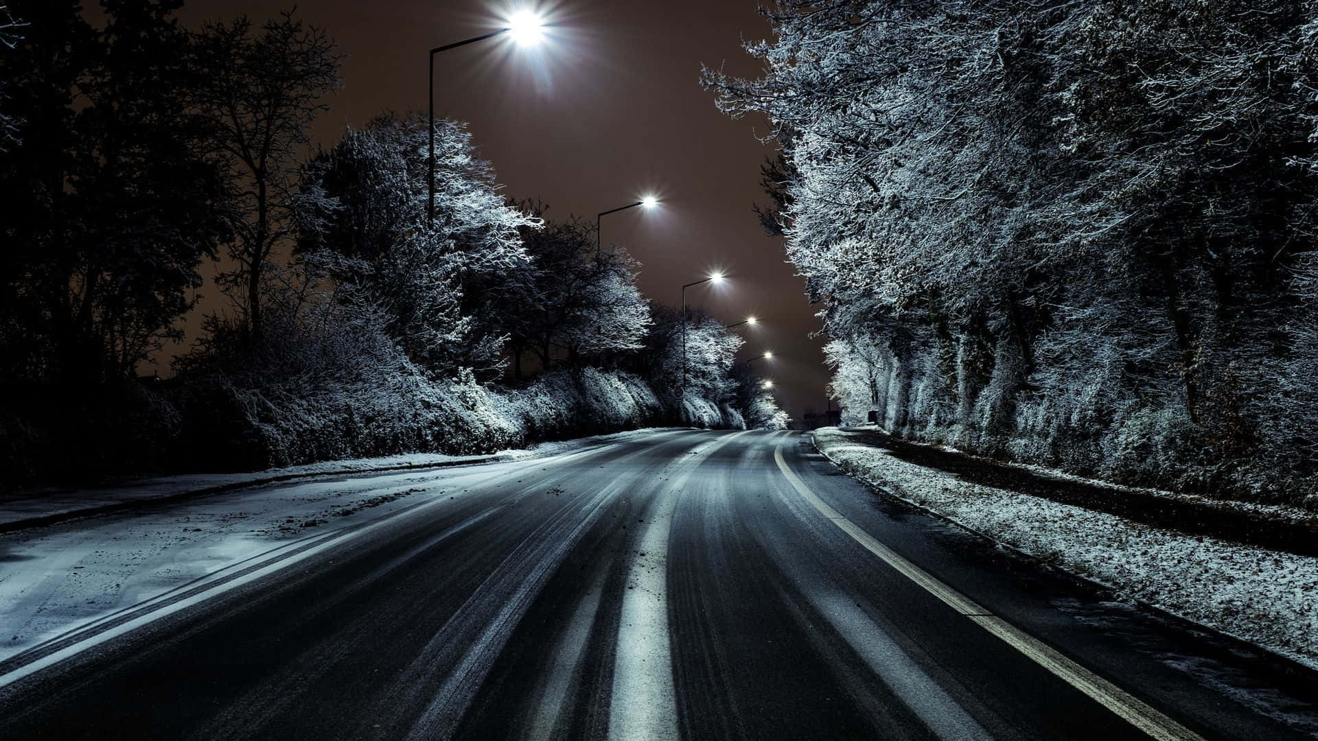 highway 桌布 壁紙 — 夜晚被街燈照亮的積雪道路，兩旁是結霜的樹木。