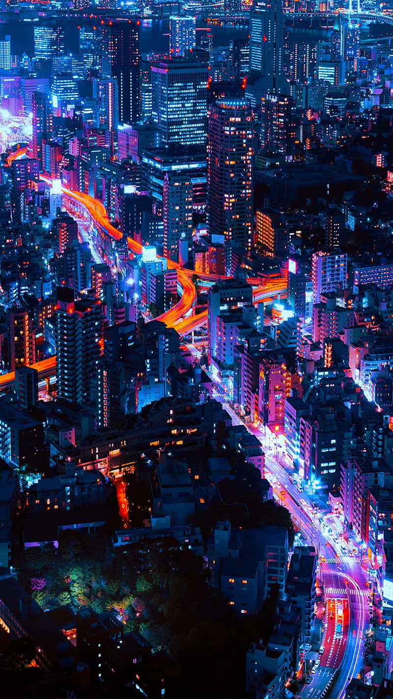 New York City Night iPhone 桌布 壁紙 — 夜晚被霓虹燈淹沒的城市景觀鳥瞰圖，有發光的高速公路和高聳的摩天大樓。