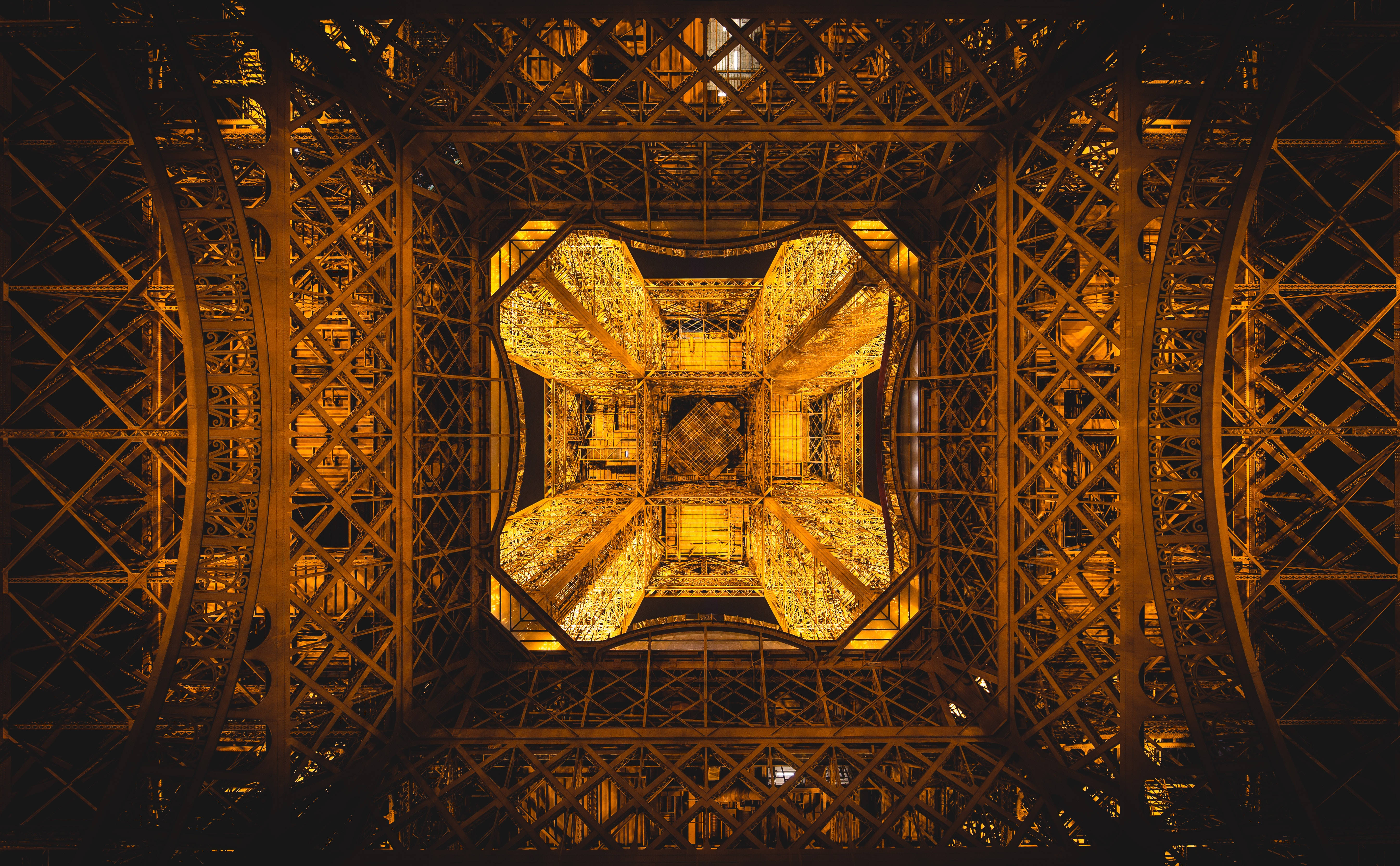 France 桌布 壁紙 — 夜晚透過艾菲爾鐵塔發光的金色格子向上看的對稱視圖。
