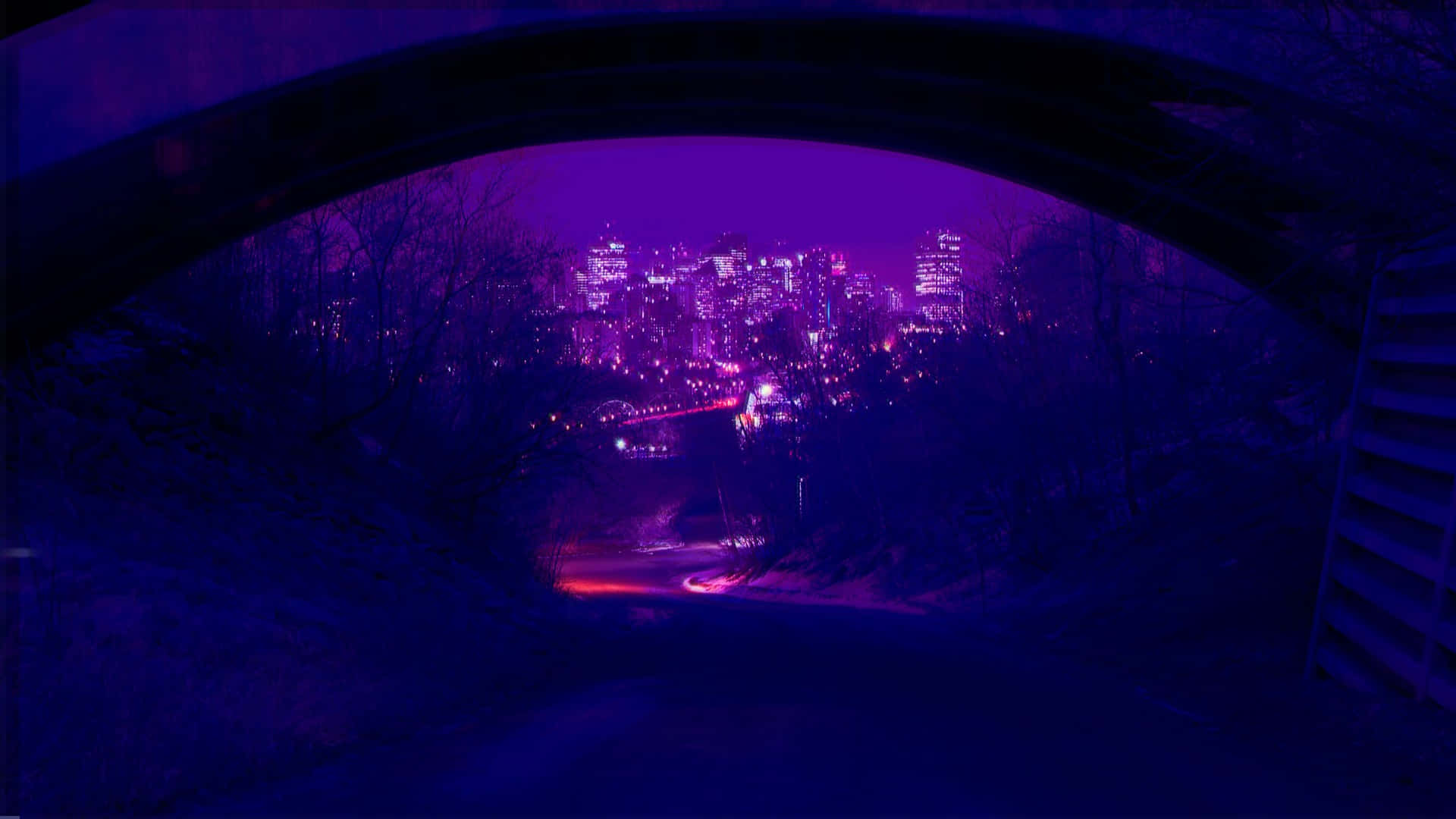 霓虹美學 桌布 壁紙 — 夜晚透過黑暗拱橋看到的充滿活力的紫色城市景觀，下方有發光的燈光和蜿蜒的道路。