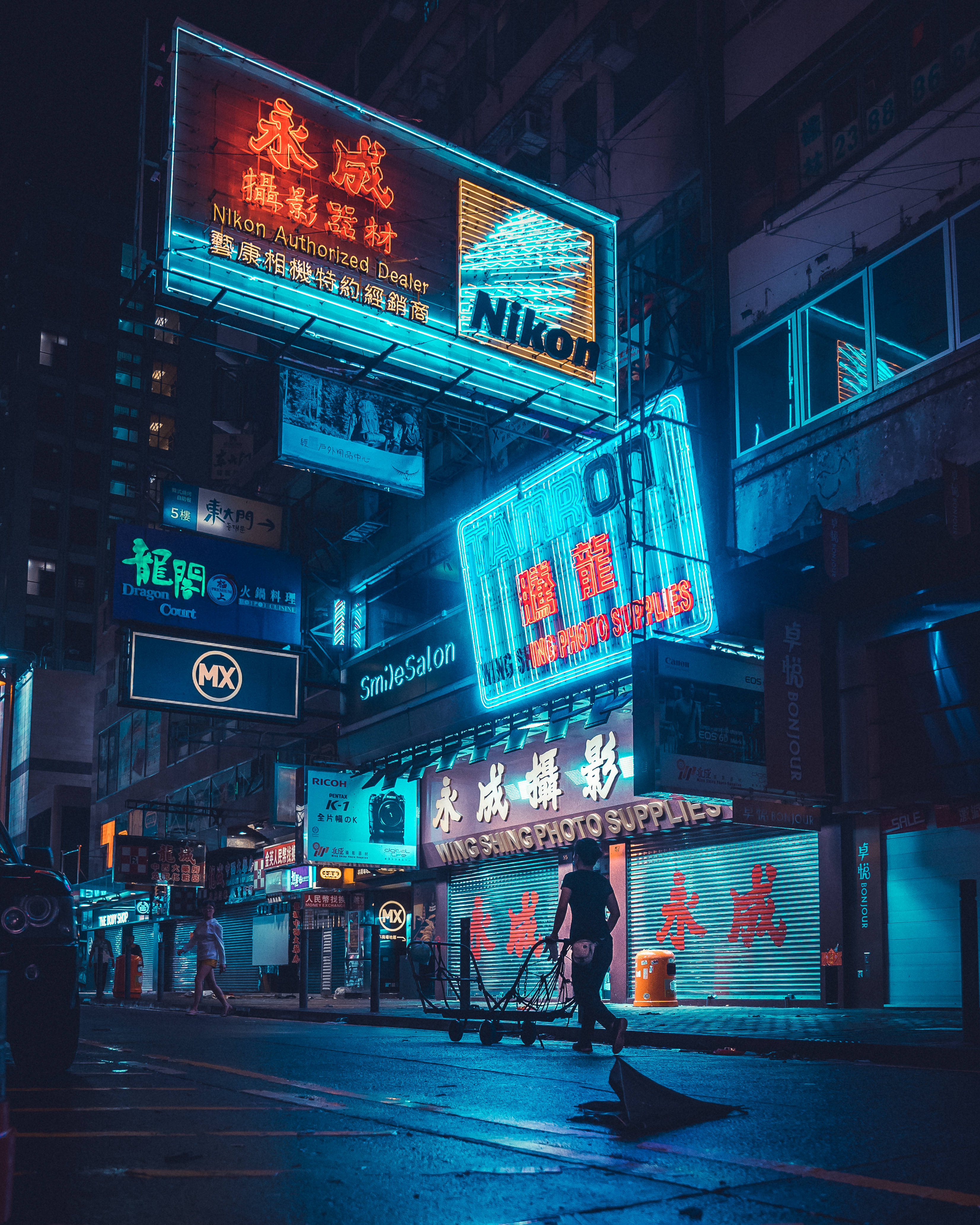 蒸氣波 桌布 壁紙 — 夜晚霓虹燈照亮嘅城市小巷，Nikon同攝影用品嘅發光招牌倒映喺濕漉漉嘅路面。