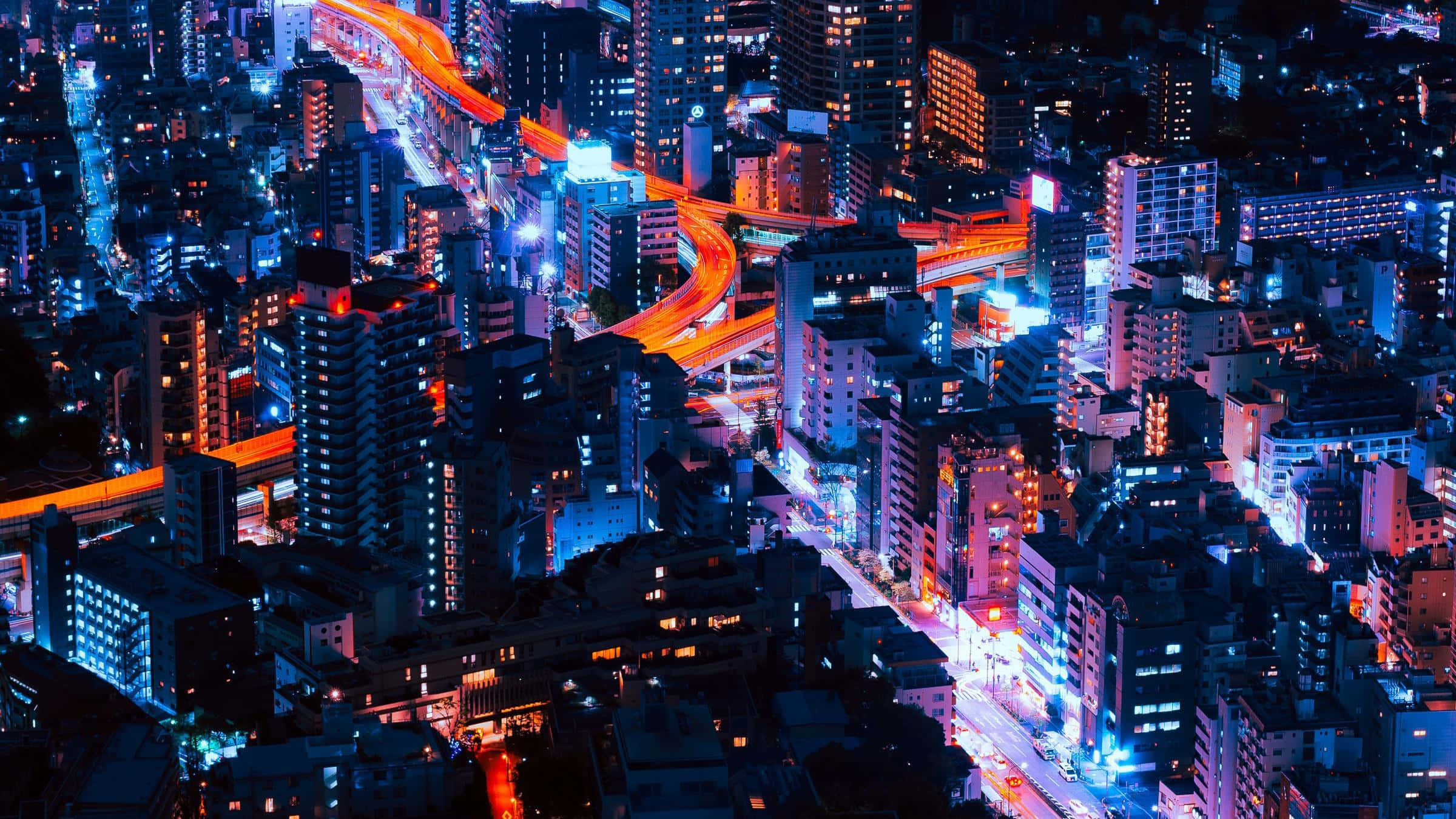 霓虹城市動態圖 桌布 壁紙 — 夜晚霓虹燈照亮城市的鳥瞰圖，發光的高速公路和密集的摩天大樓。