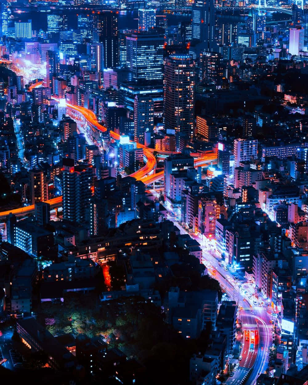 City View 桌布 壁紙 — 夜晚霓虹燈照亮城市的鳥瞰圖，發光的高速公路和高聳的摩天大樓。