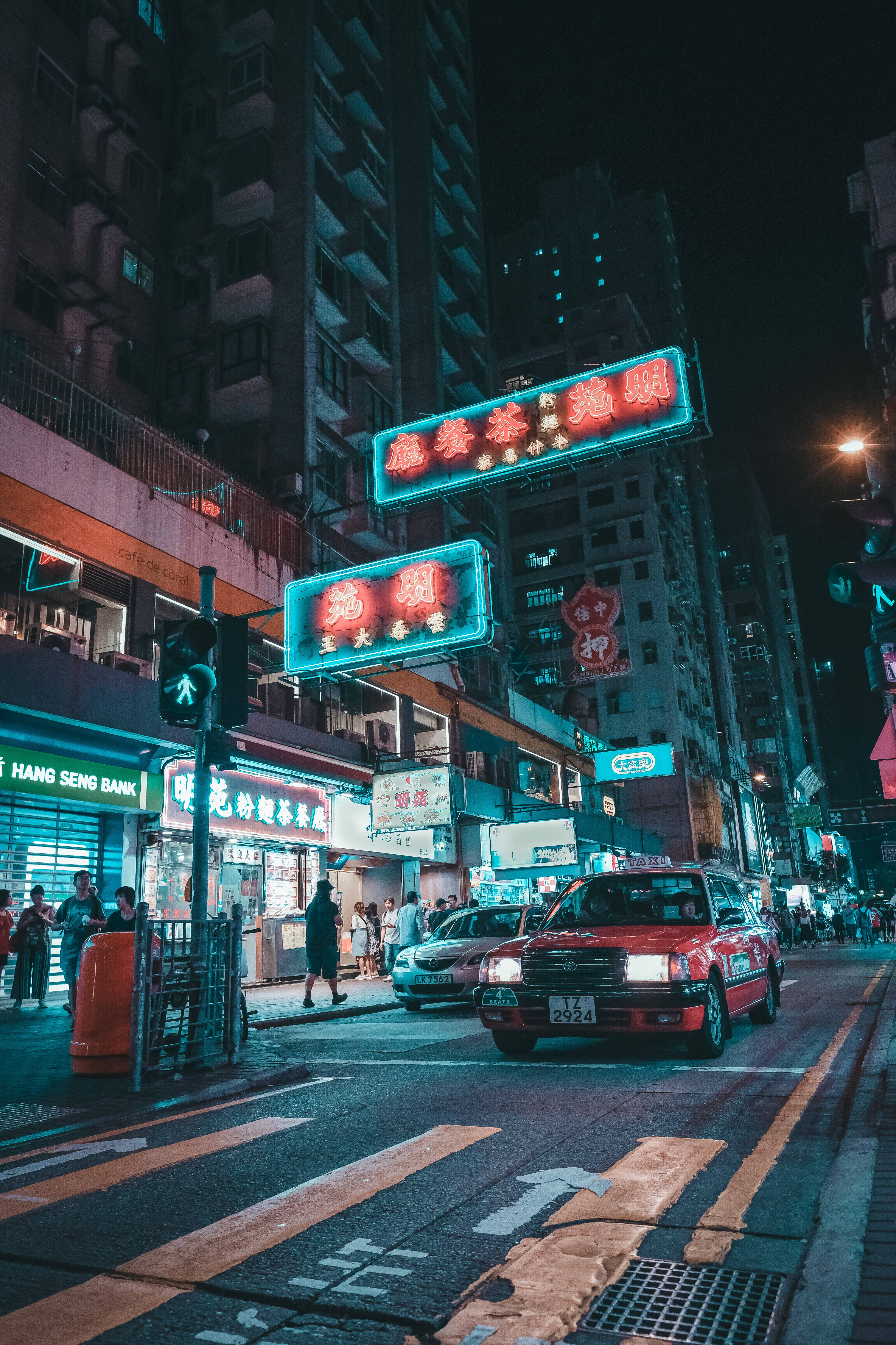 neon sign 桌布 壁紙 — 夜晚霓虹燈照亮的城市街道，有發光的招牌和紅色計程車在繁忙的交通中穿梭。