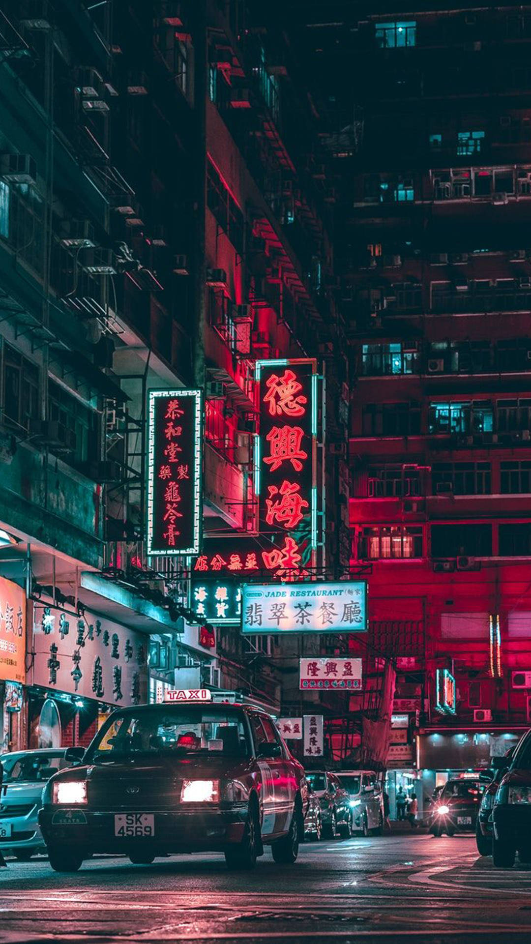 Aesthetic iPhone Xr 桌布 壁紙 — 夜晚霓虹燈照亮的城市街道，紅色和藍色的發光招牌在潮濕的路面上反射，汽車駛過。