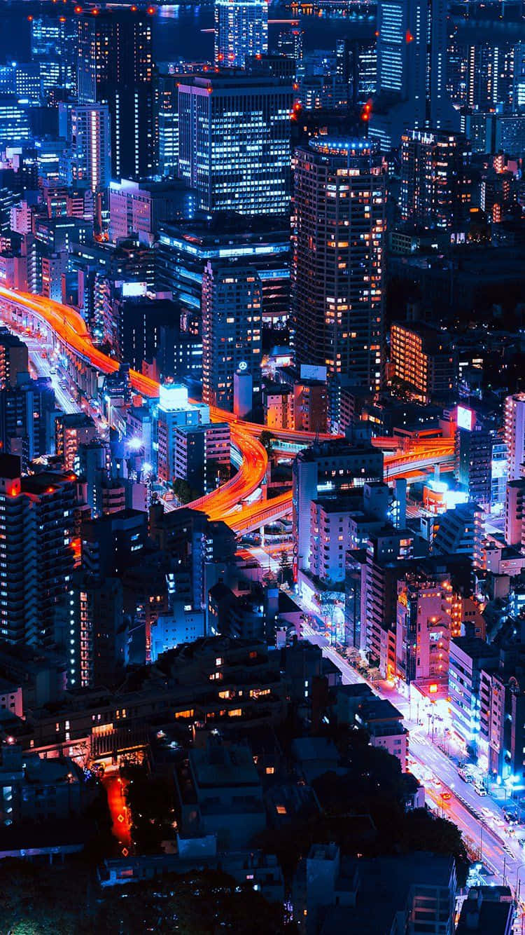 City iPhone 桌布 壁紙 — 夜晚霓虹燈照亮的天際線鳥瞰圖，有發光的摩天大樓和橙色車流燈光。