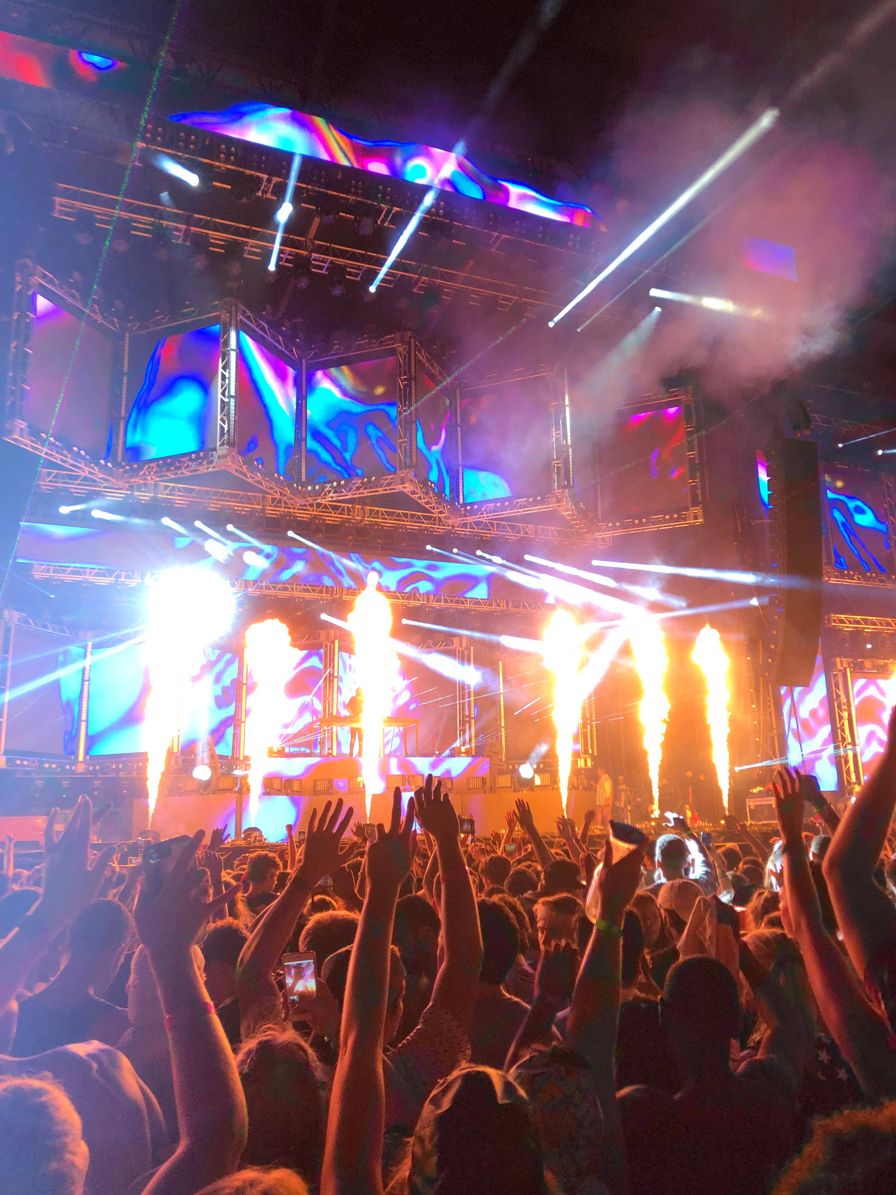 Lollapalooza 桌布 壁紙 — 夜晚音樂會的人群，上方有熾熱的煙火和發光的舞台燈光。