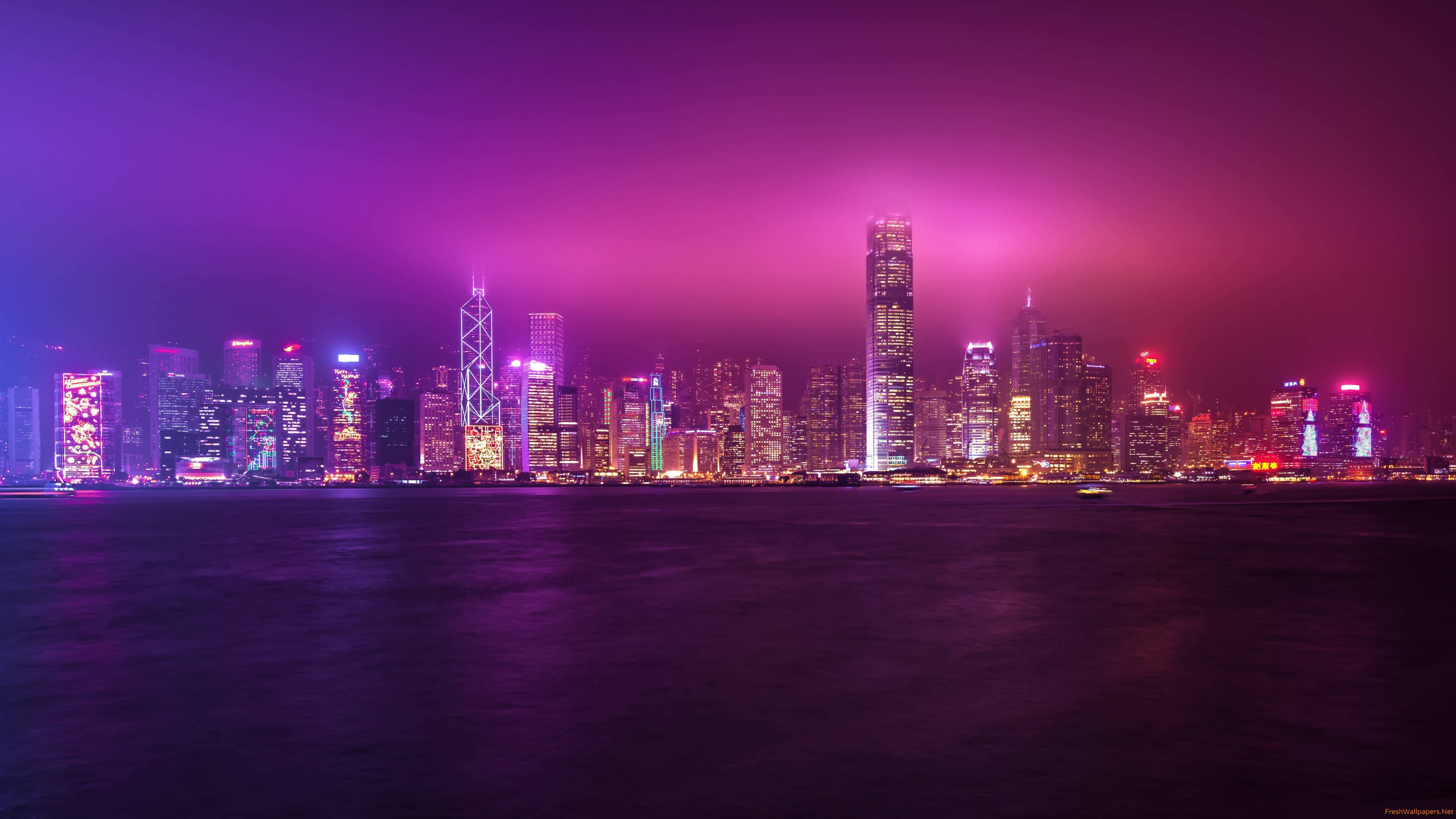 Non Copyrighted 桌布 壁紙 — 夜晚香港的天際線，充滿活力的紫色和粉紅色霓虹燈，倒映在下方平靜的水面上。