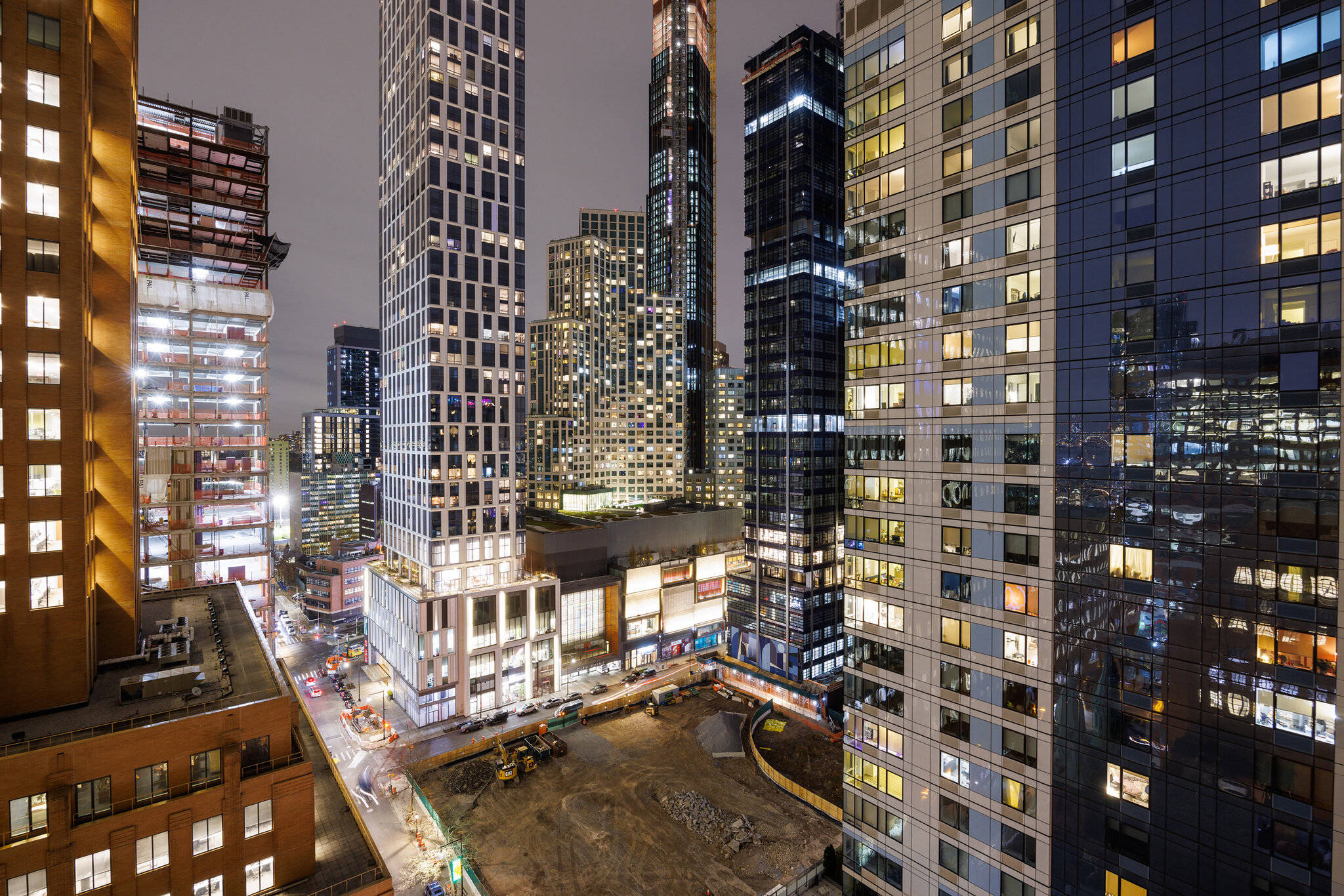 New York 桌布 壁紙 — 夜晚高聳摩天大樓的鳥瞰圖，窗戶發光，下方有建築工地。