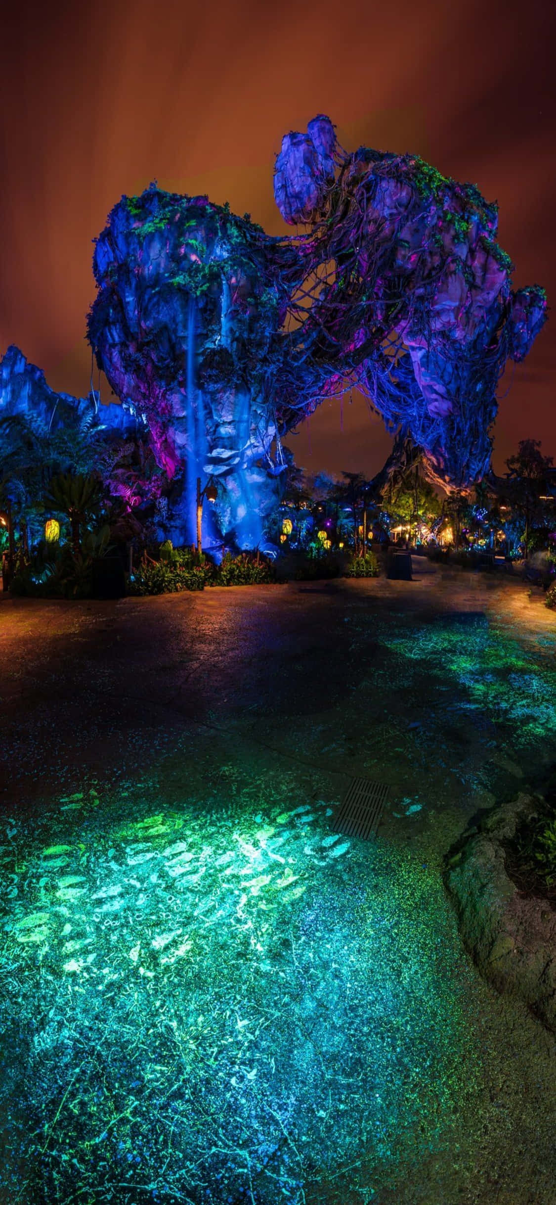 walt disney 桌布 壁紙 — 夜晚高聳的發光藍色岩石形成，鮮豔的藍綠色光線反射在潮濕的地面上。