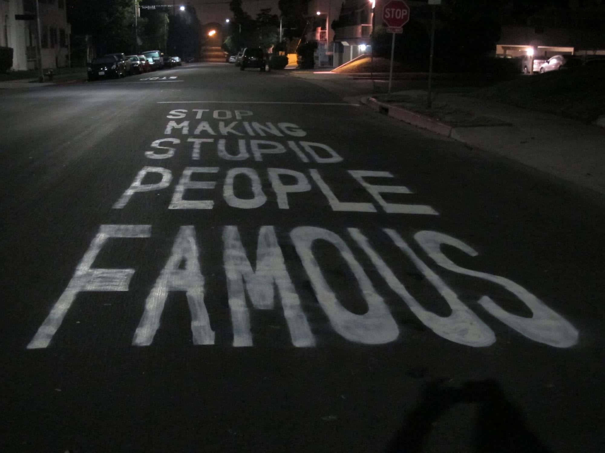 dumb 桌布 壁紙 — 夜晚黑暗街道上的大型白色塗鴉文字寫著：停止讓愚蠢的人出名。