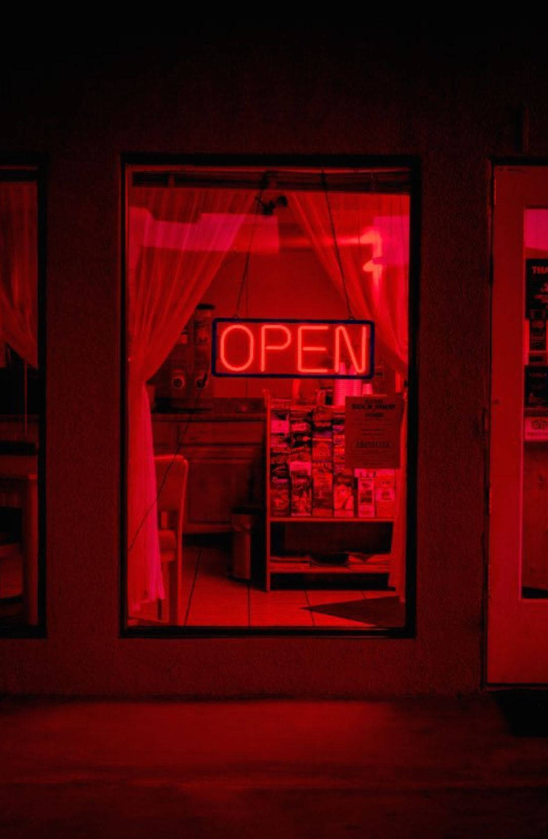 暗紅色 桌布 壁紙 — 夜間，一個發光的紅色霓虹燈「OPEN」標誌透過商店櫥窗投射出詭異的光芒，照亮了窗簾和內部貨架。