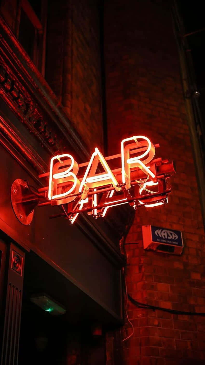 Neon Red Aesthetic 桌布 壁紙 — 夜間，一個發光的紅色霓虹燈酒吧招牌在磚牆上投射出溫暖的光芒。