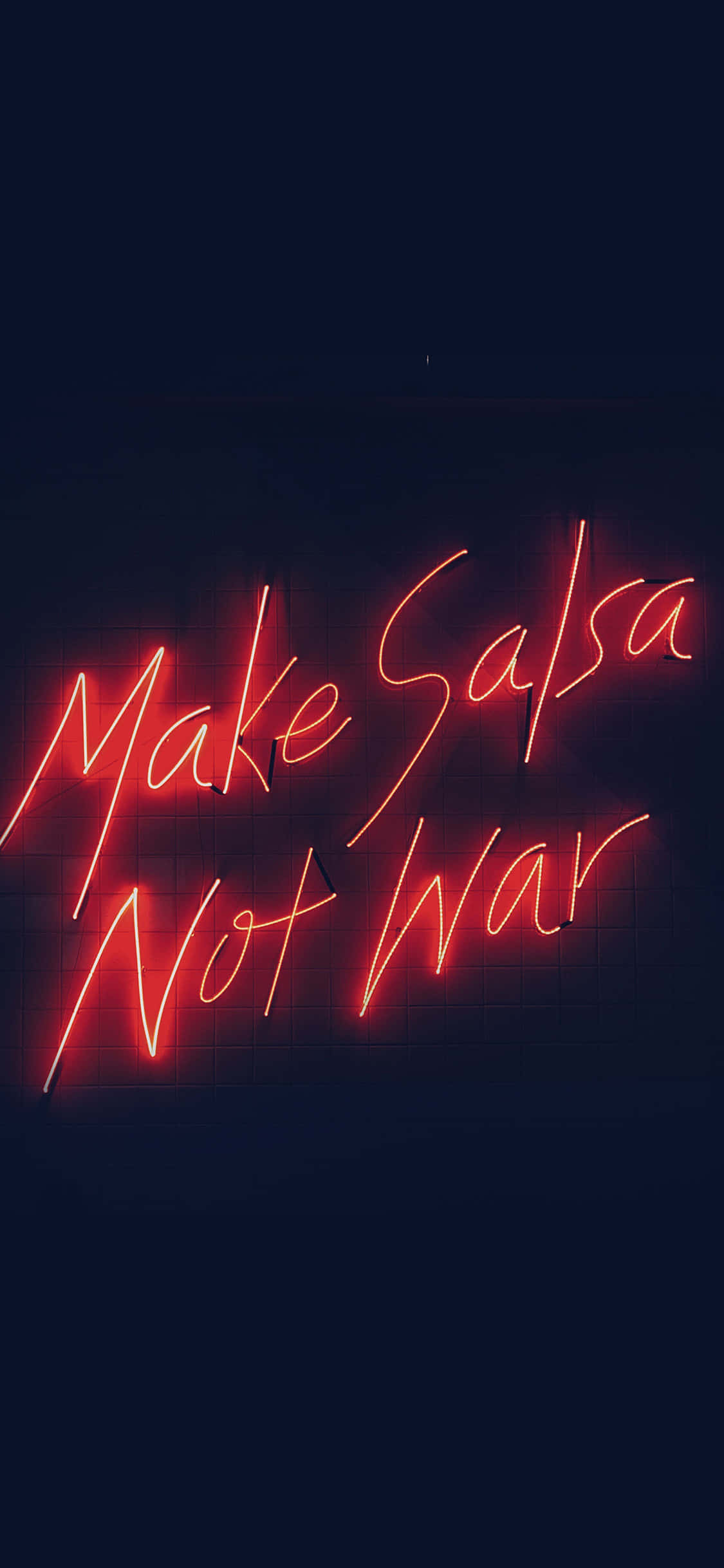 Red Neon 桌布 壁紙 — 夜間，一個鮮豔的紅色霓虹燈牌寫著 'Make Salsa Not War'，在深色磚牆上發光。