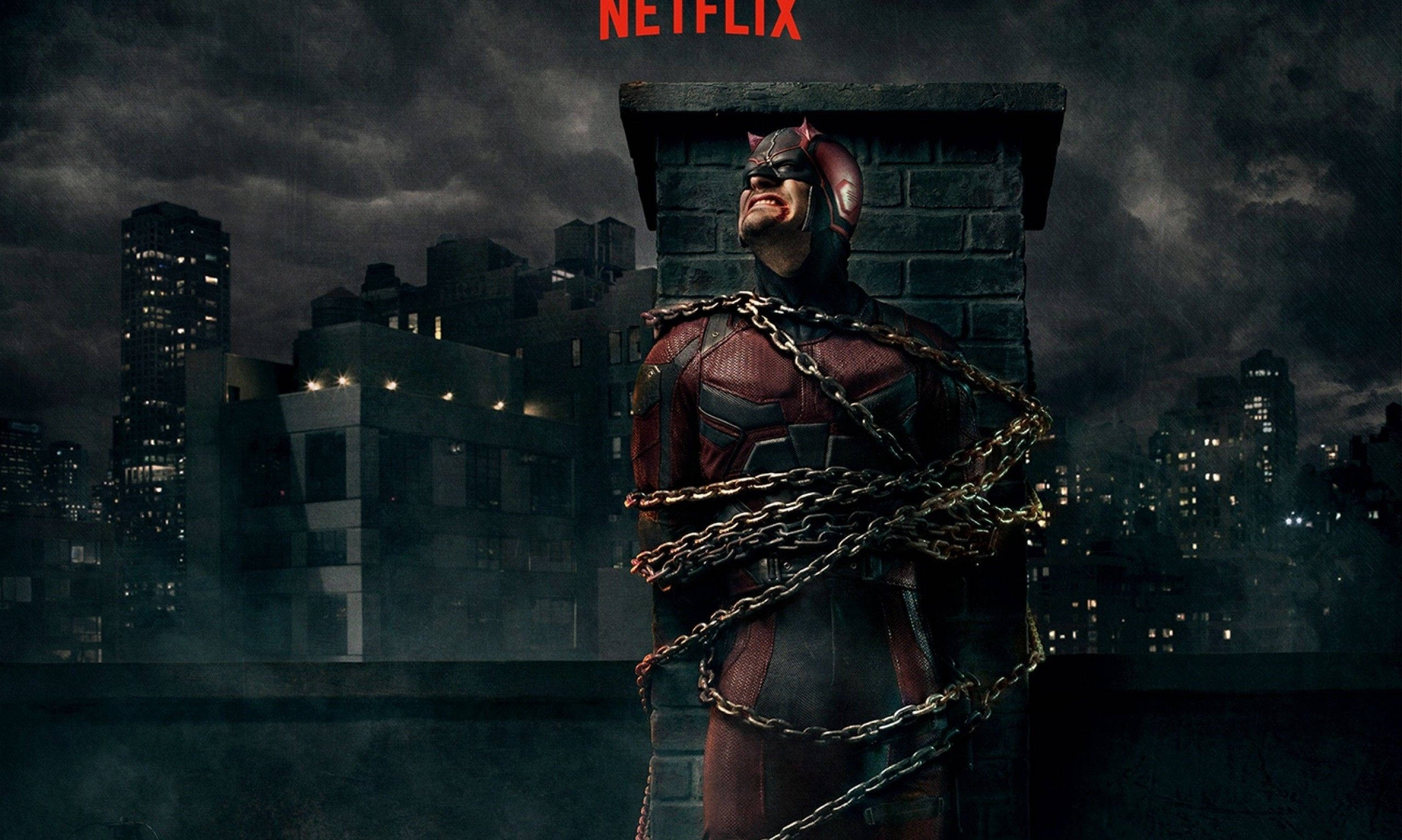 Netflix 桌布 壁紙 — 夜間，夜魔俠被鎖鏈綁在屋頂上，背景是暴風雨的城市天際線。