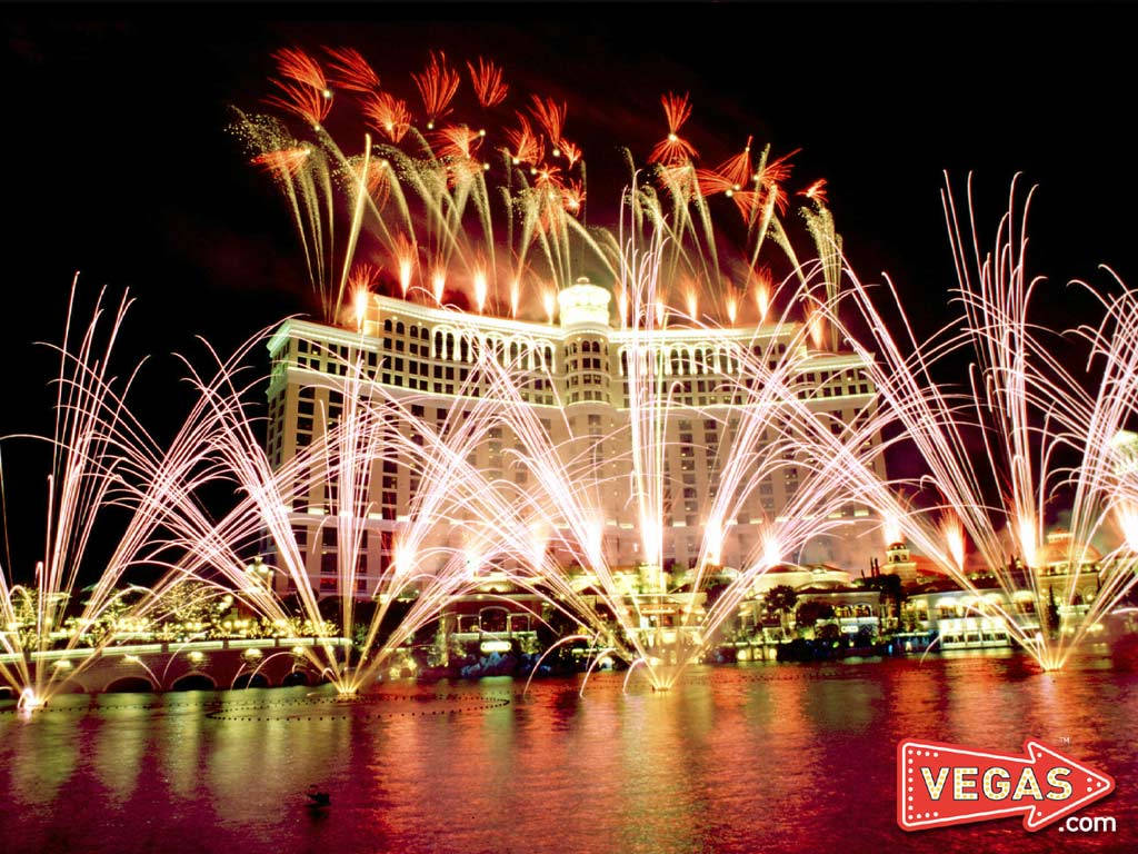 Fireworks 桌布 壁紙 — 夜間，煙火在倒映在水面上的宏偉酒店上空綻放出鮮豔的紅色和白色。