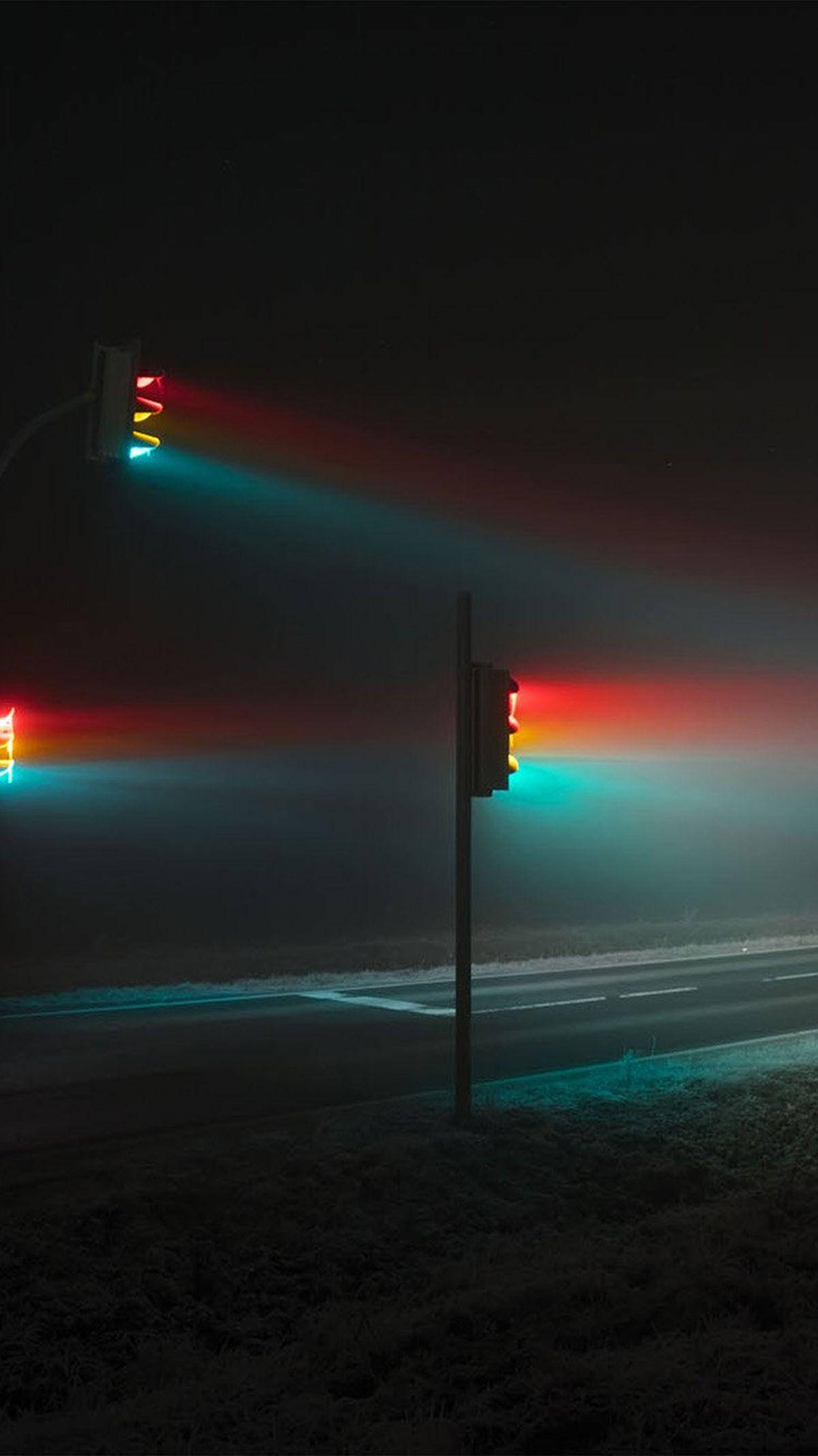 Gradient 桌布 壁紙 — 夜間交通號誌在霧氣瀰漫的道路上投射出鮮豔的紅色和藍綠色光束，營造出荒涼的城市環境。