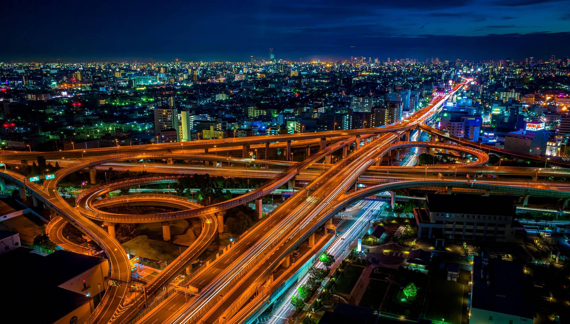 夜間俯瞰複雜的高速公路交匯處，帶有發光的交通軌跡。
