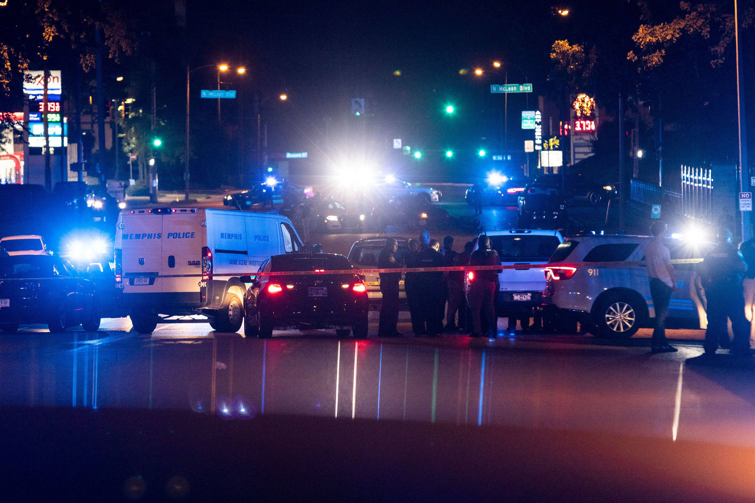 城市 桌布 壁紙 — 夜間城市街道場景，警車閃爍燈光，警員站在犯罪現場的封鎖線後。
