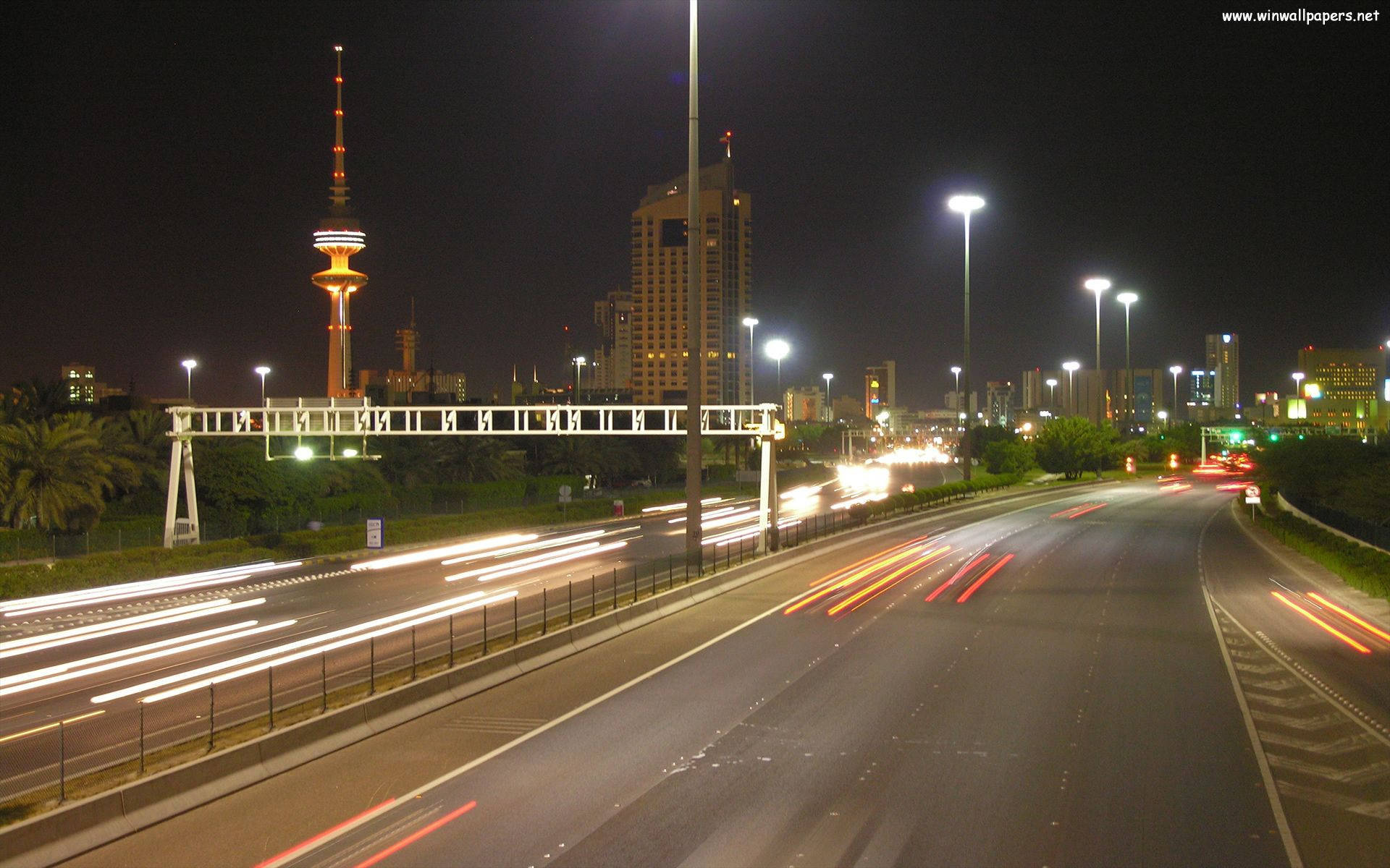 科威特 桌布 壁紙 — 夜間城市高速公路，有汽車的光跡和遠處的發光塔。